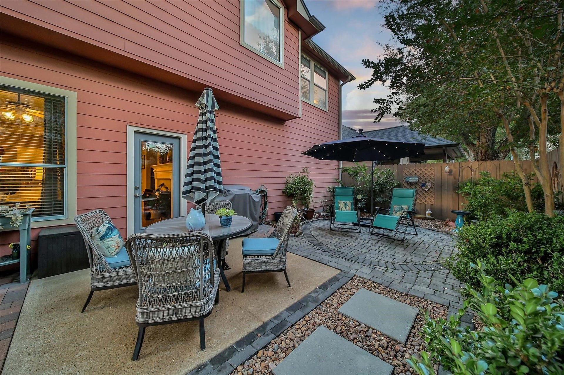 Charming backyard with a cobblestone patio area, mature trees, and cozy seating, perfect for relaxation or entertaining in a peaceful setting.