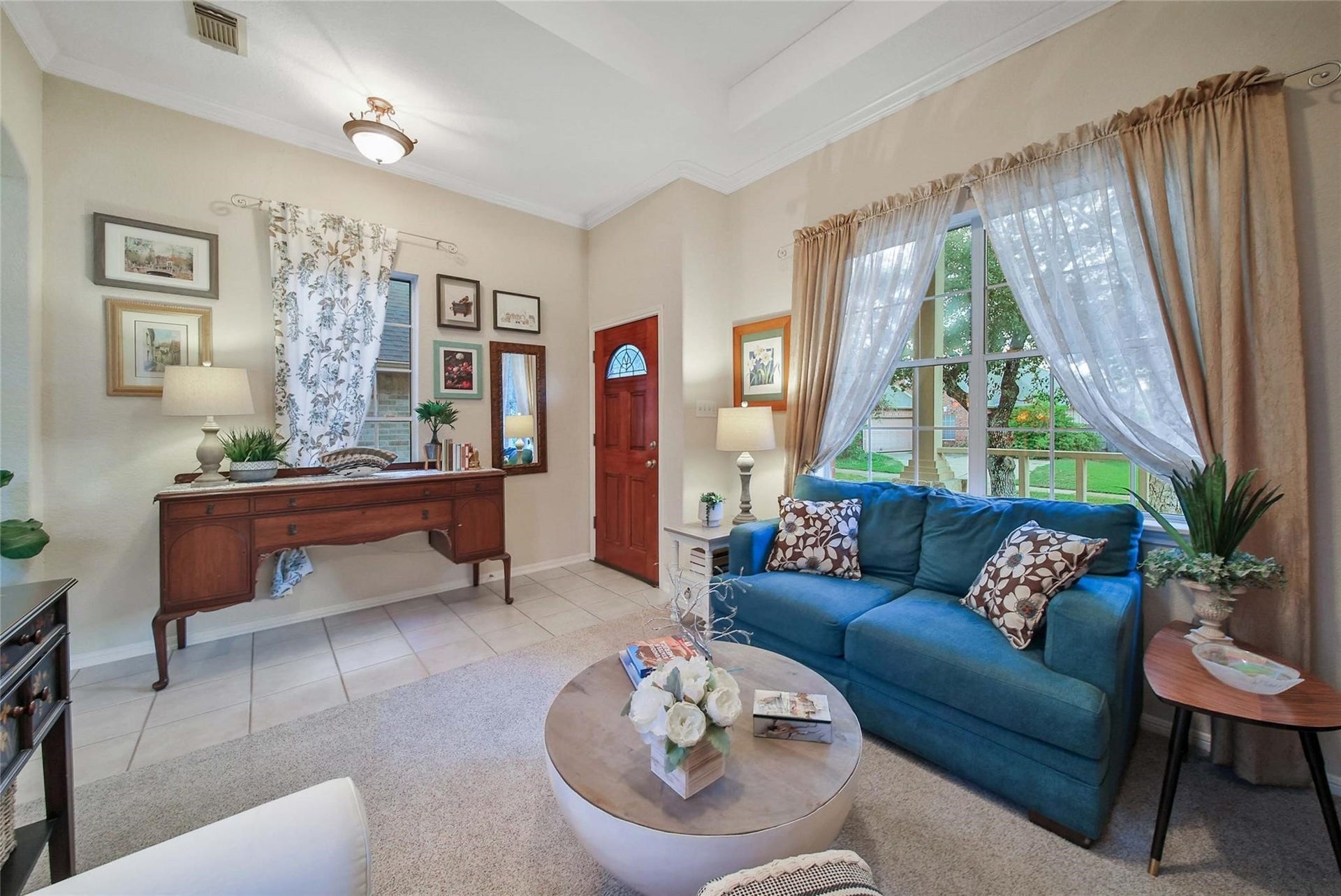 Cozy and well-lit living room with tasteful decor, featuring elegant curtains, and a view of the greenery outside.