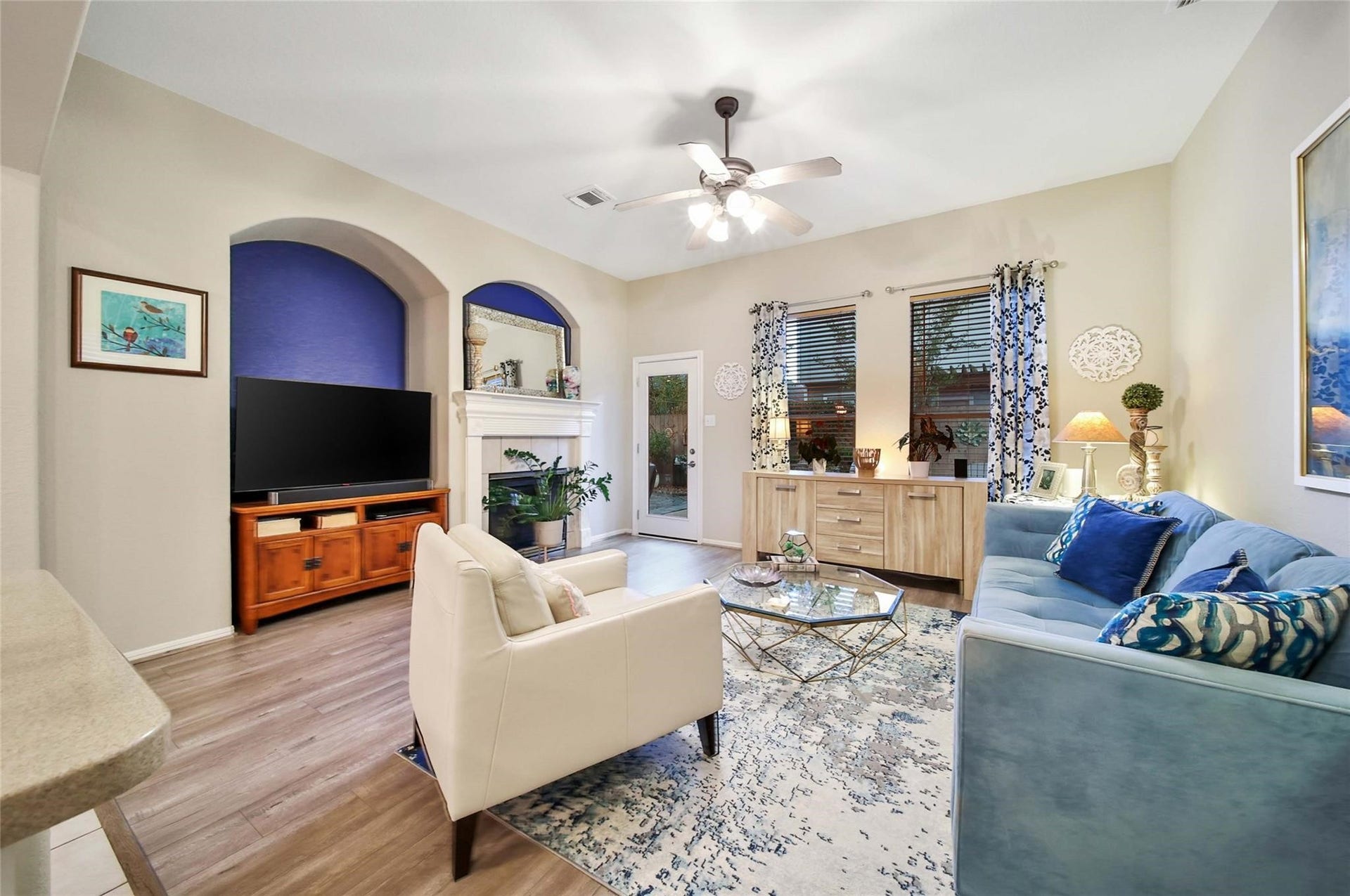 This is a bright and inviting open-concept living space . The room is well-lit with natural light and modern ceiling fixtures, complemented by warm wood flooring.