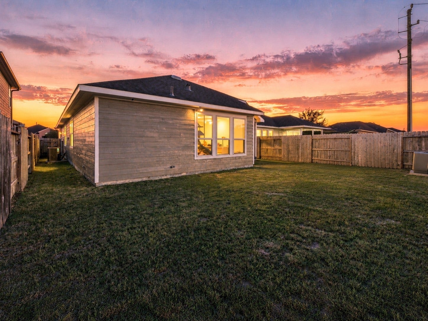 7814 Tindarey Maple Trace, Richmond, TX 77407 Evening view highlights the home's rear exterior, illuminated windows, and spacious outdoor setting.