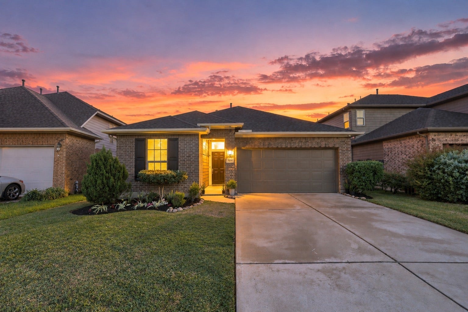 7814 Tindarey Maple Trace, Richmond, TX 77407 Inviting front elevation highlighted by exterior lighting, landscaped grounds, and a welcoming covered entry.