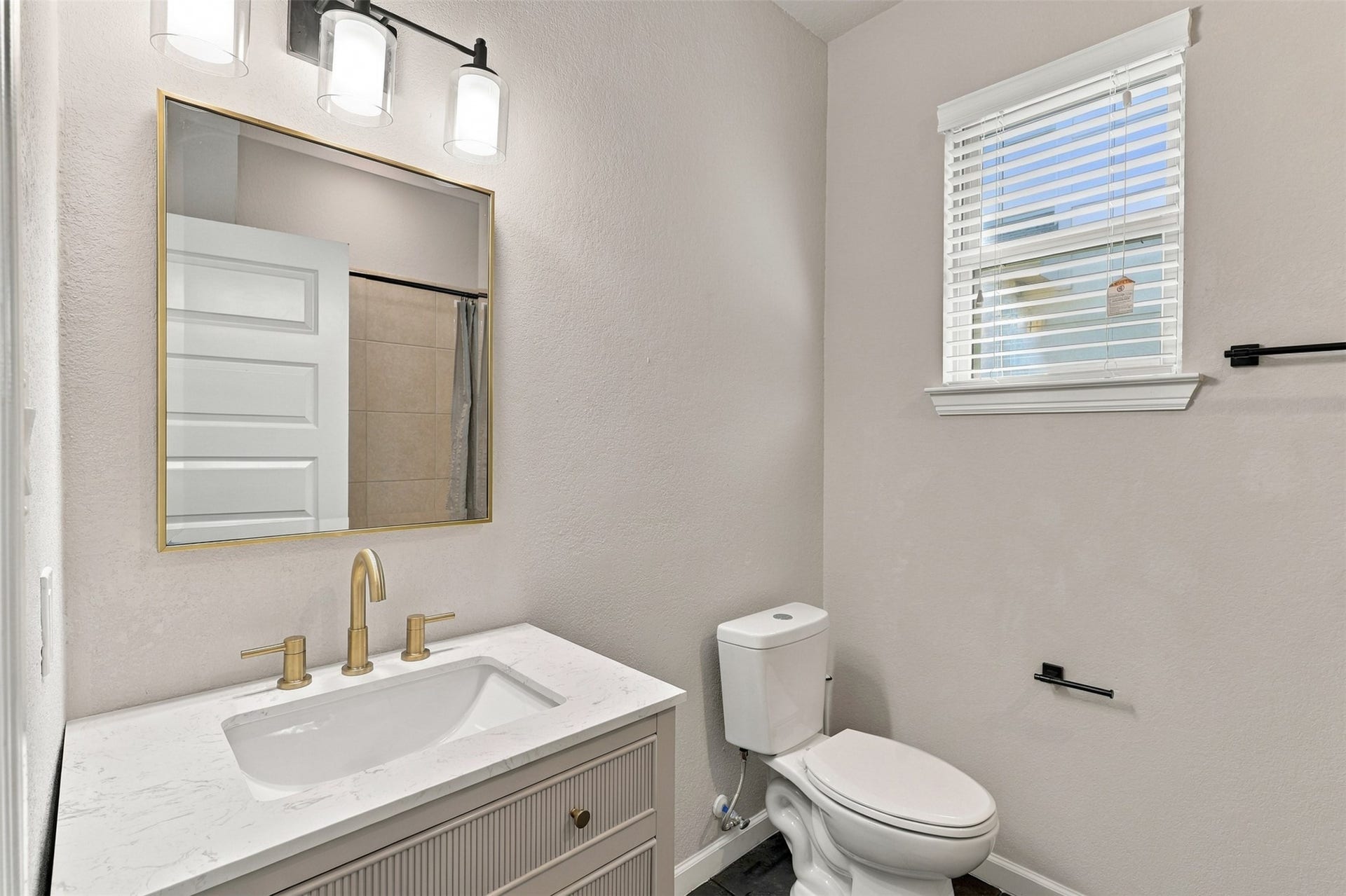 7814 Tindarey Maple Trace, Richmond, TX 77407 Secondary bathroom featuring a modern vanity, gold-tone fixtures, and a window for natural light.