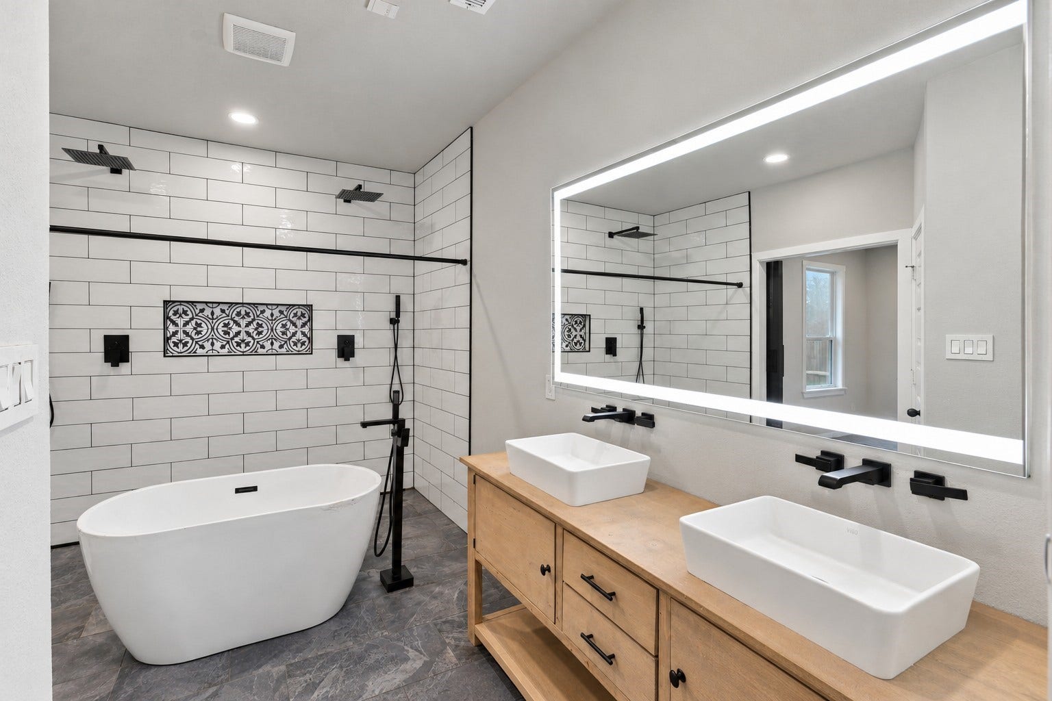 7814 Tindarey Maple Trace, Richmond, TX 77407 Double vessel sinks, a wood vanity, illuminated mirror, and matte-black fixtures complete the primary bath.