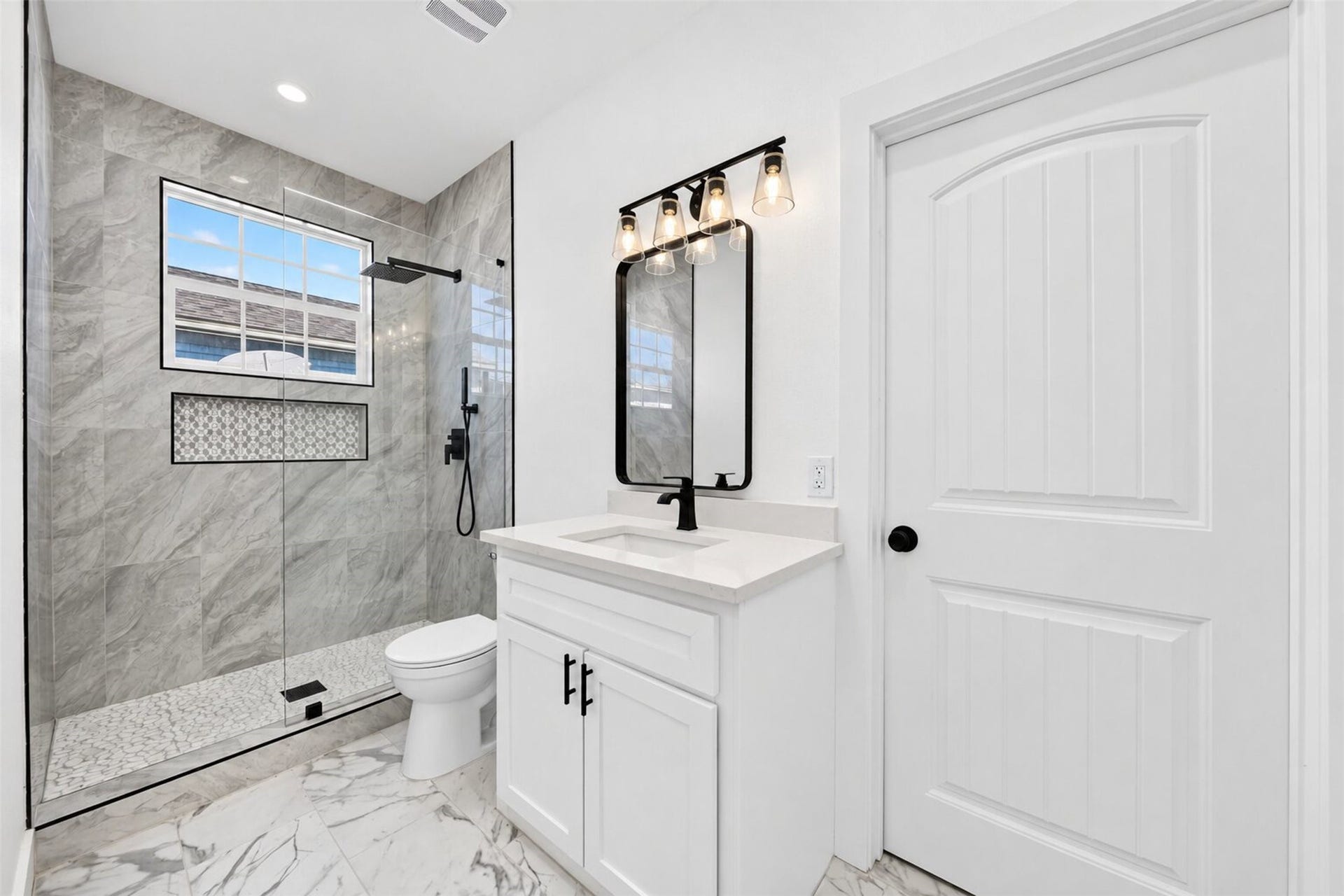 This stunning bathroom boasts a sophisticated design, featuring a glass-enclosed shower, an
elegant vanity with black finishes, and tile flooring, all contributing to a clean and modern aesthetic.