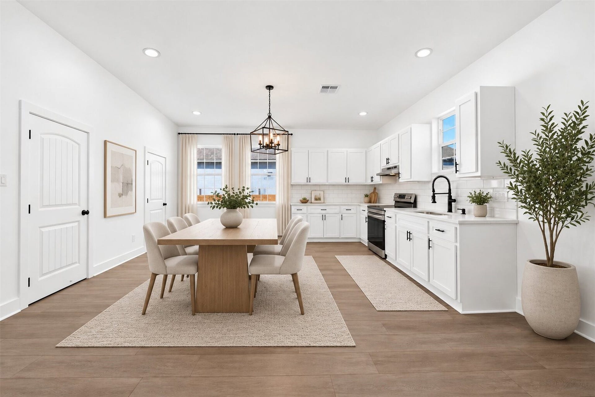 The kitchen boasts contemporary white cabinetry,stainless steel appliances, and laminate flooring. It is bright and spacious, featuring recessed lighting and a large windows positioned above sink and adjacent to breakfast area.