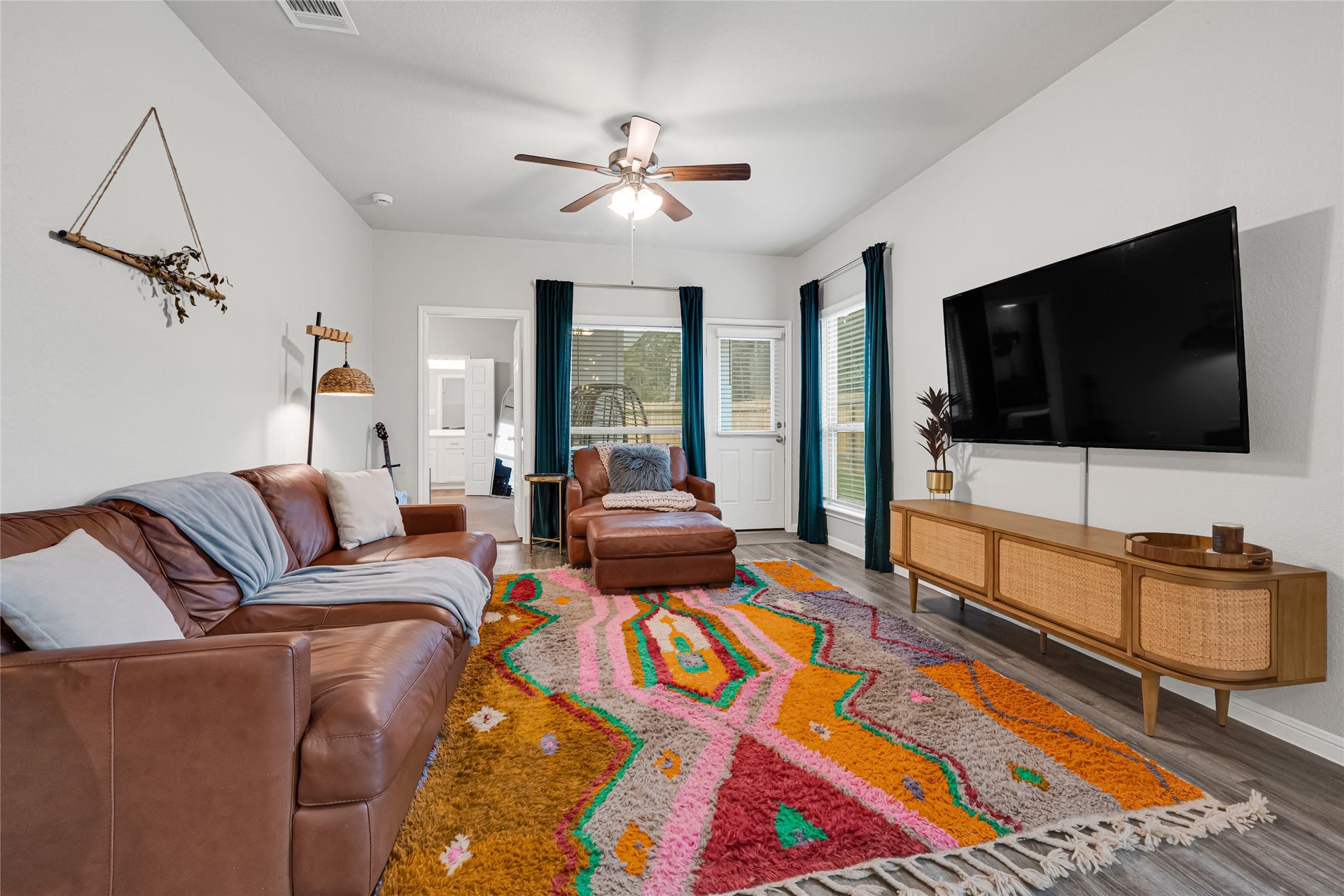 515 Emerald Thicket Lane, Houston, TX 77336 Cozy living room with a modern feel, featuring natural light streaming through large windows with designer curtains, and a decorative ceiling fan provides all the comforts you want to enjoy your living area.