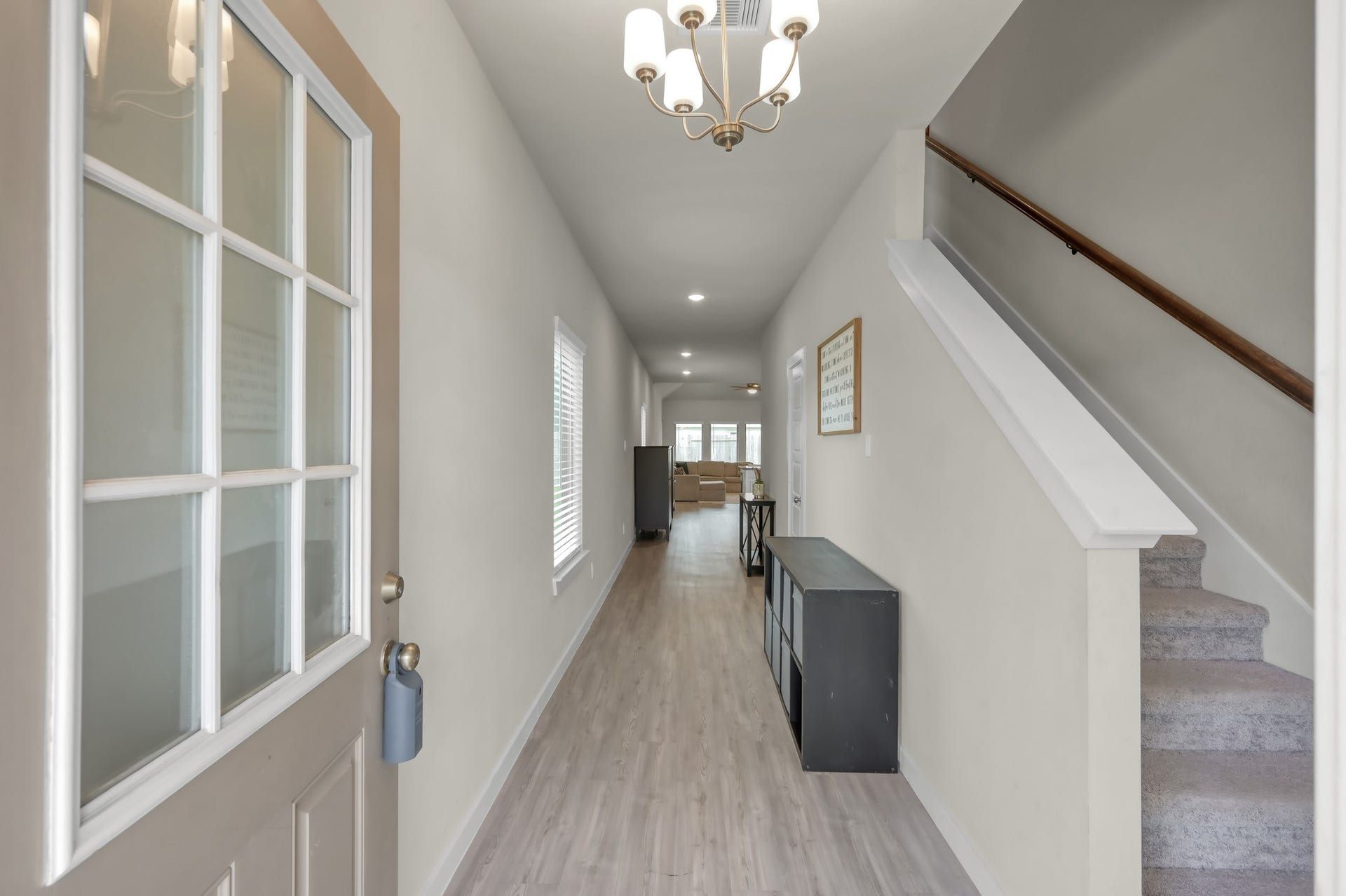 22203 Cardinal Crest Lane, New Caney, TX 77357 Bright entryway with light wood flooring, modern chandelier, and a staircase leading upstairs. The hallway opens into a spacious living area, offering a welcoming first impression.