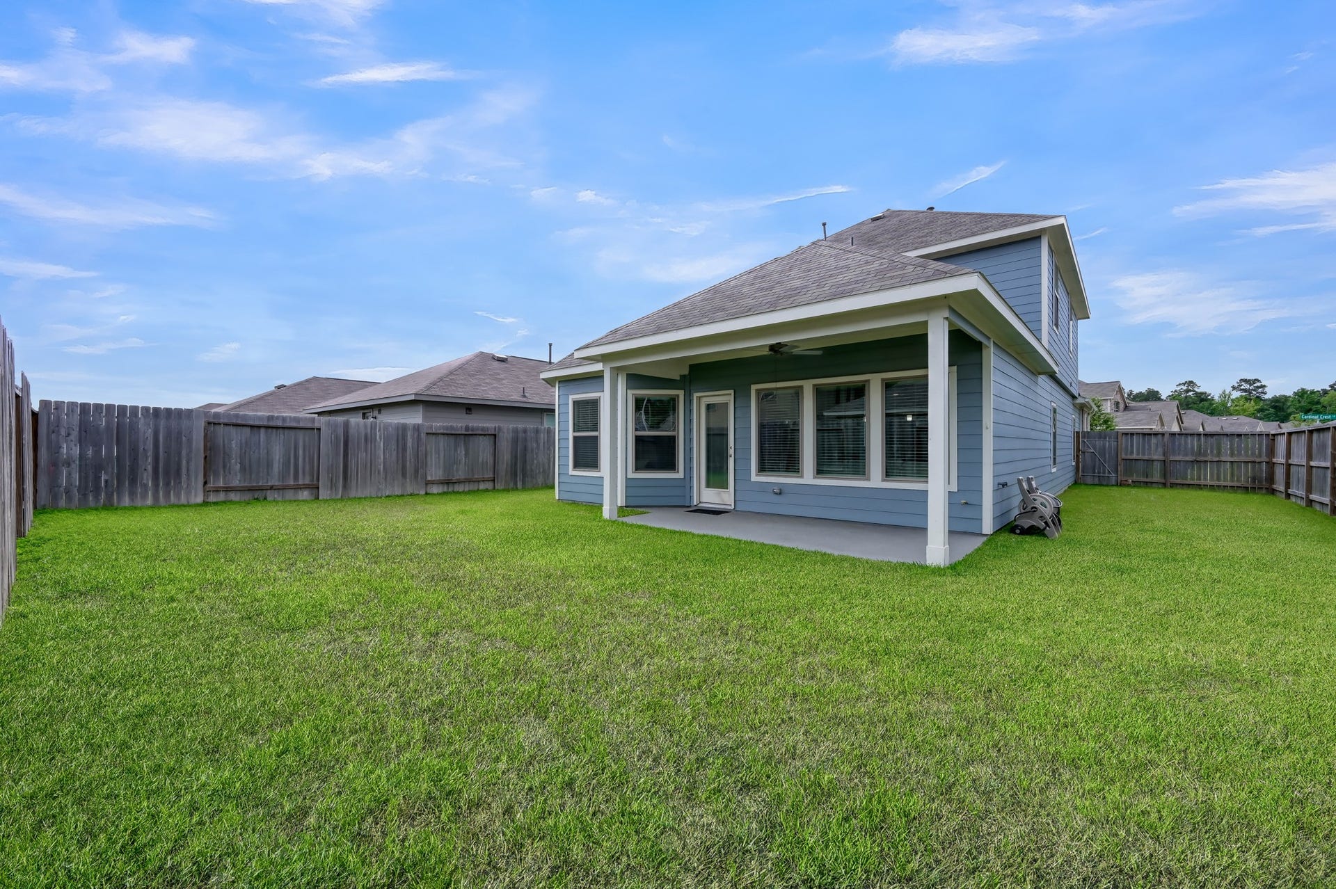 22203 Cardinal Crest Lane, New Caney, TX 77357 This photo showcases a spacious backyard with a well-maintained lawn, a covered patio area, and a fenced perimeter, providing privacy and ample outdoor space for activities.
