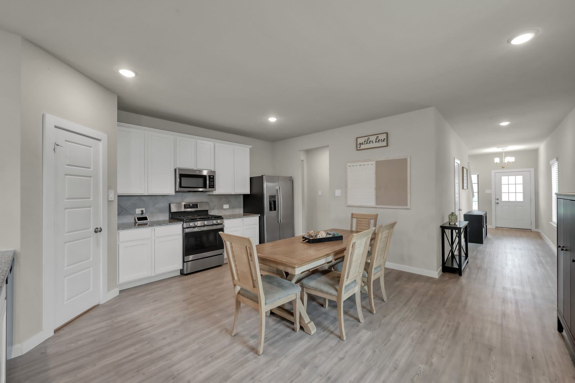 22203 Cardinal Crest Lane, New Caney, TX 77357 This modern, open-concept kitchen and dining area with light wood flooring. The kitchen features white cabinetry, stainless steel appliances, and a sleek design. The dining space includes a wooden table with chairs, and the area is well-lit with recessed lighting, providing a warm and inviting atmosphere.