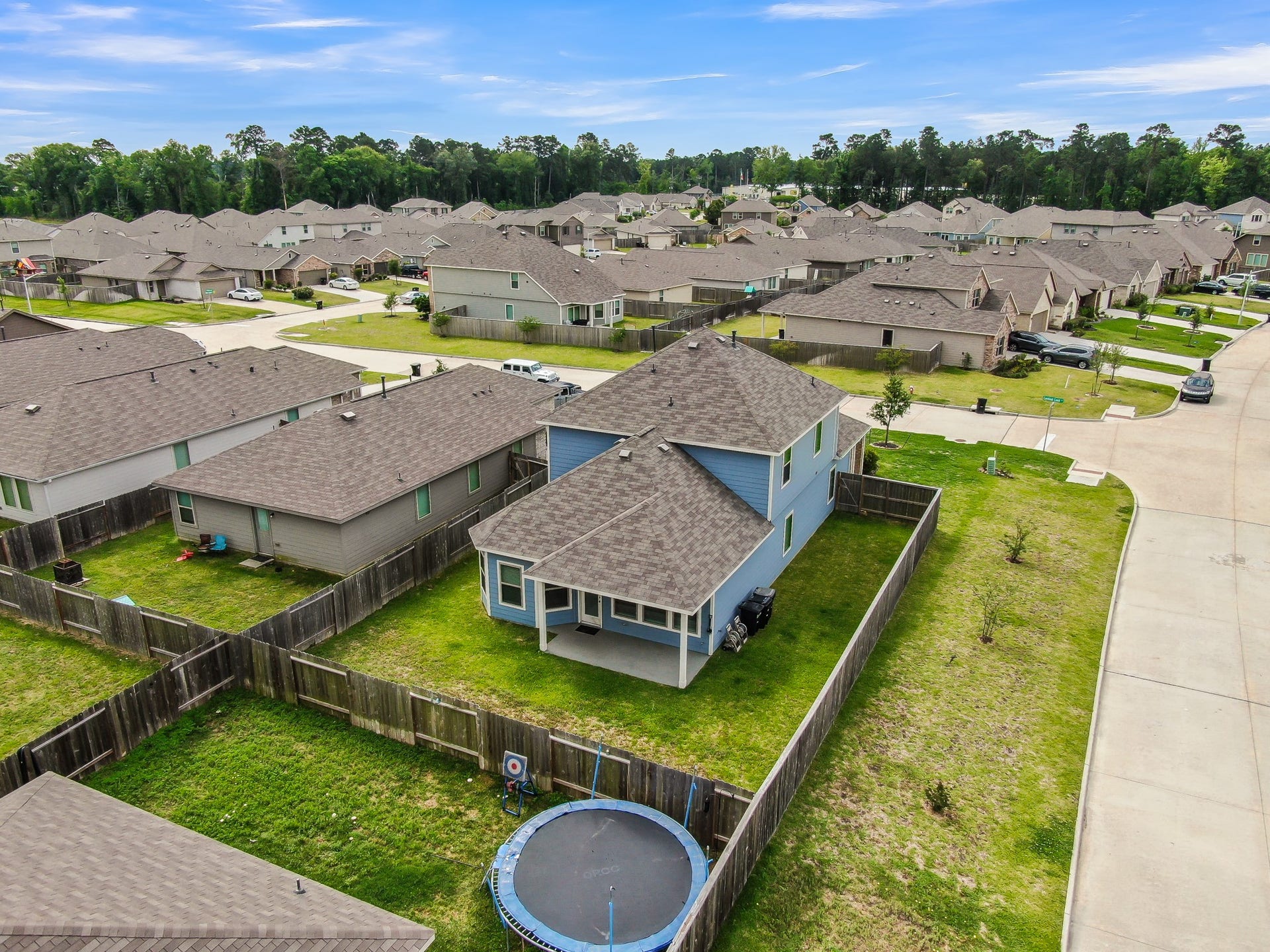 22203 Cardinal Crest Lane, New Caney, TX 77357 Charming two-story home with a spacious fenced backyard, perfect for families. The neighborhood features well-maintained homes and lush green surroundings, offering a tranquil suburban feel.