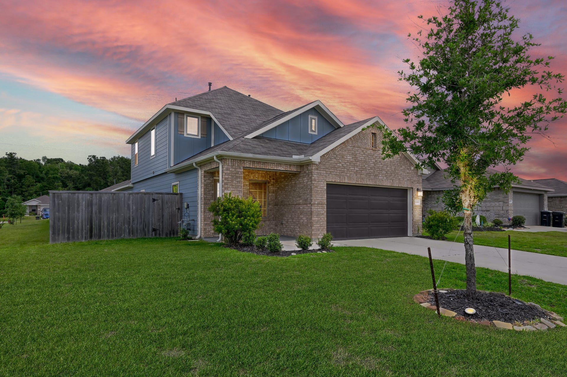 22203 Cardinal Crest Lane, New Caney, TX 77357 This charming two-story home features a modern design with a combination of brick and siding. It has a well-maintained front yard, a spacious driveway, and a two-car garage. The backdrop of a stunning sunset enhances its curb appeal.