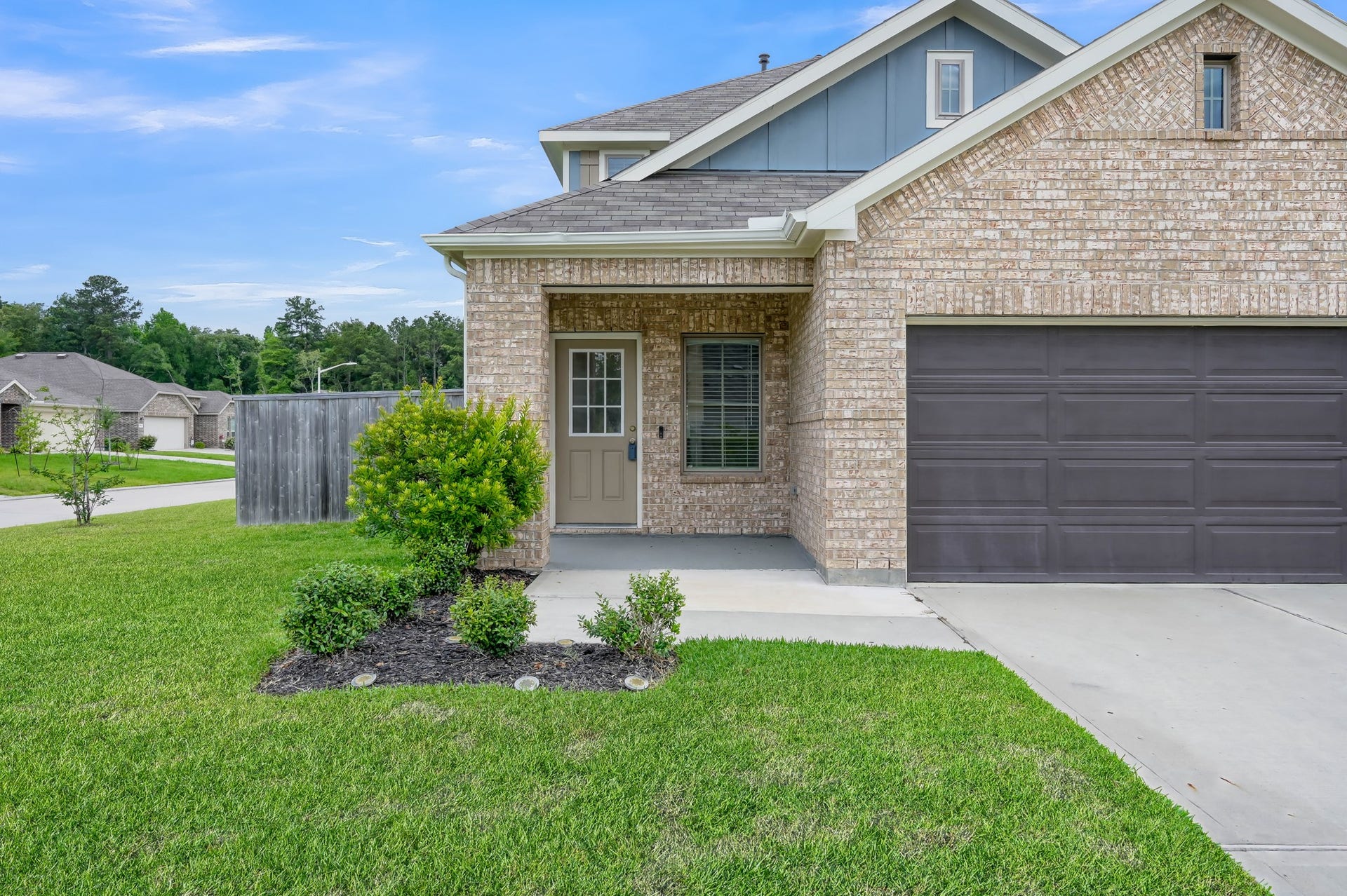 22203 Cardinal Crest Lane, New Caney, TX 77357 This is a modern brick home featuring a two-car garage and a small front porch. The exterior is well-maintained with a tidy lawn and landscaped shrubs, situated on a corner lot in a quiet neighborhood.
