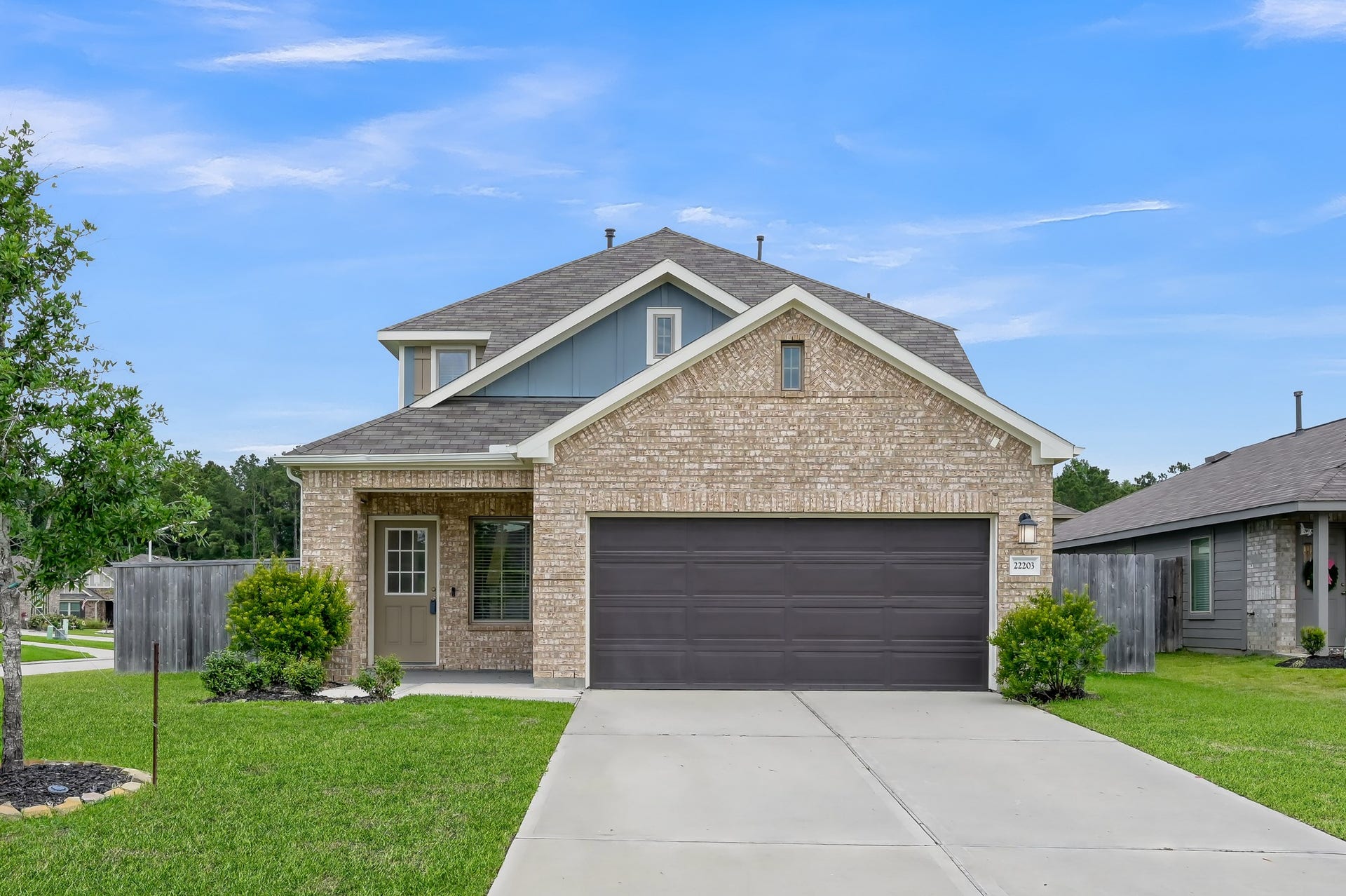 22203 Cardinal Crest Lane, New Caney, TX 77357 A modern two-story brick house with a two-car garage and a neatly maintained front yard. The home has a welcoming porch and is situated in a suburban neighborhood.