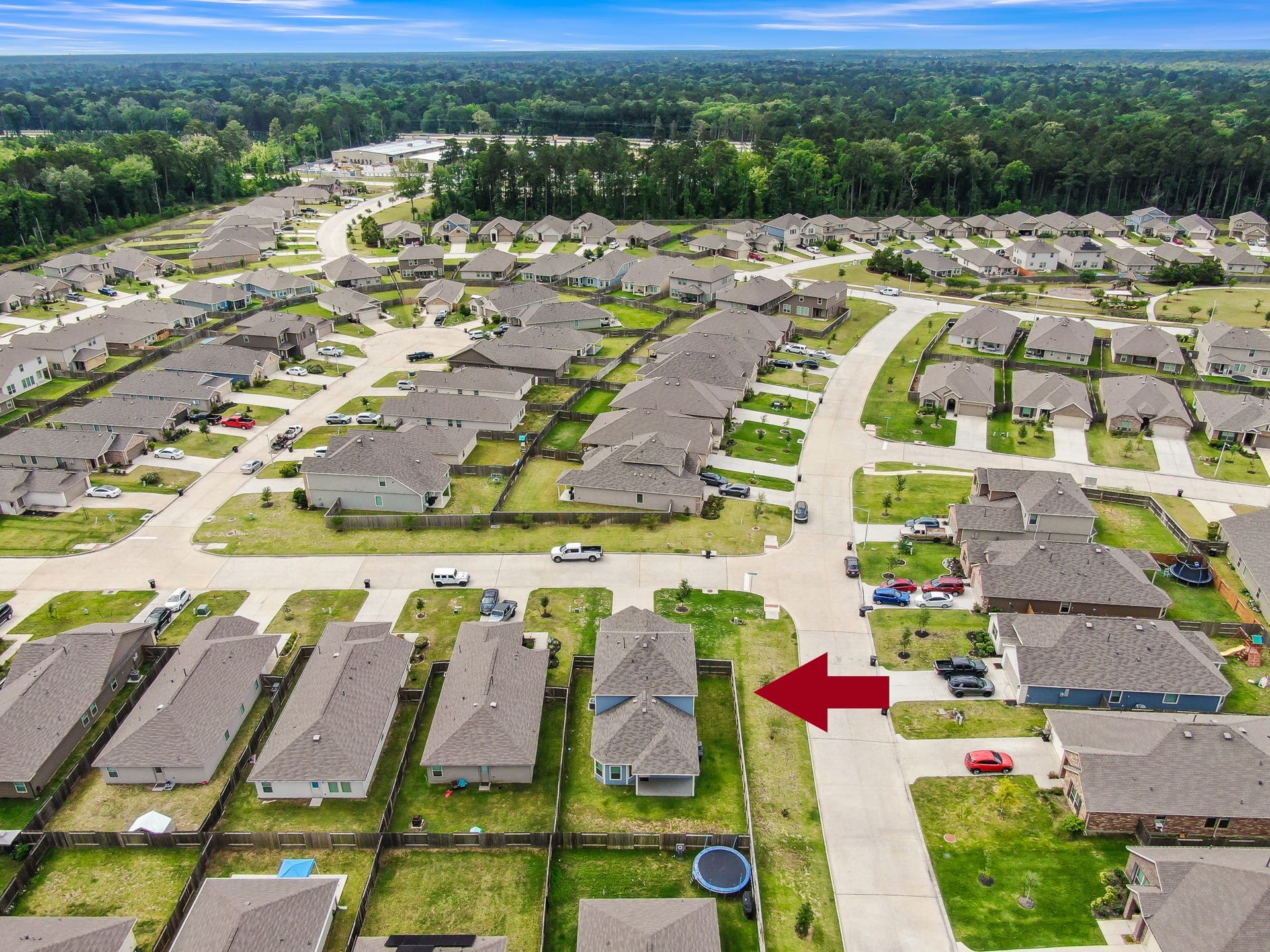 22203 Cardinal Crest Lane, New Caney, TX 77357 This aerial photo shows a suburban neighborhood with neatly arranged single-family homes. The highlighted house has a fenced backyard, nearby green spaces, and is situated in a quiet, well-maintained community.