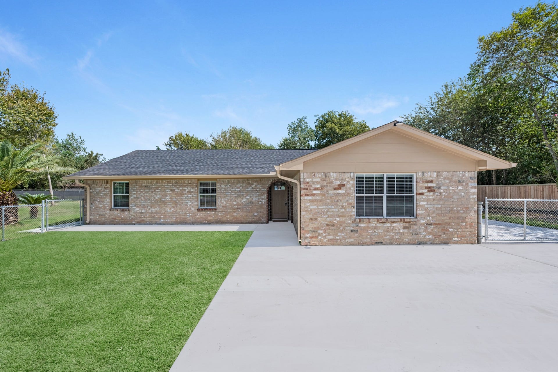 17435 Wells Drive, #CR115, Pearland, TX 77584 Pulling up to the home, a wide driveway leads to the brick exterior and a well-kept front lawn.