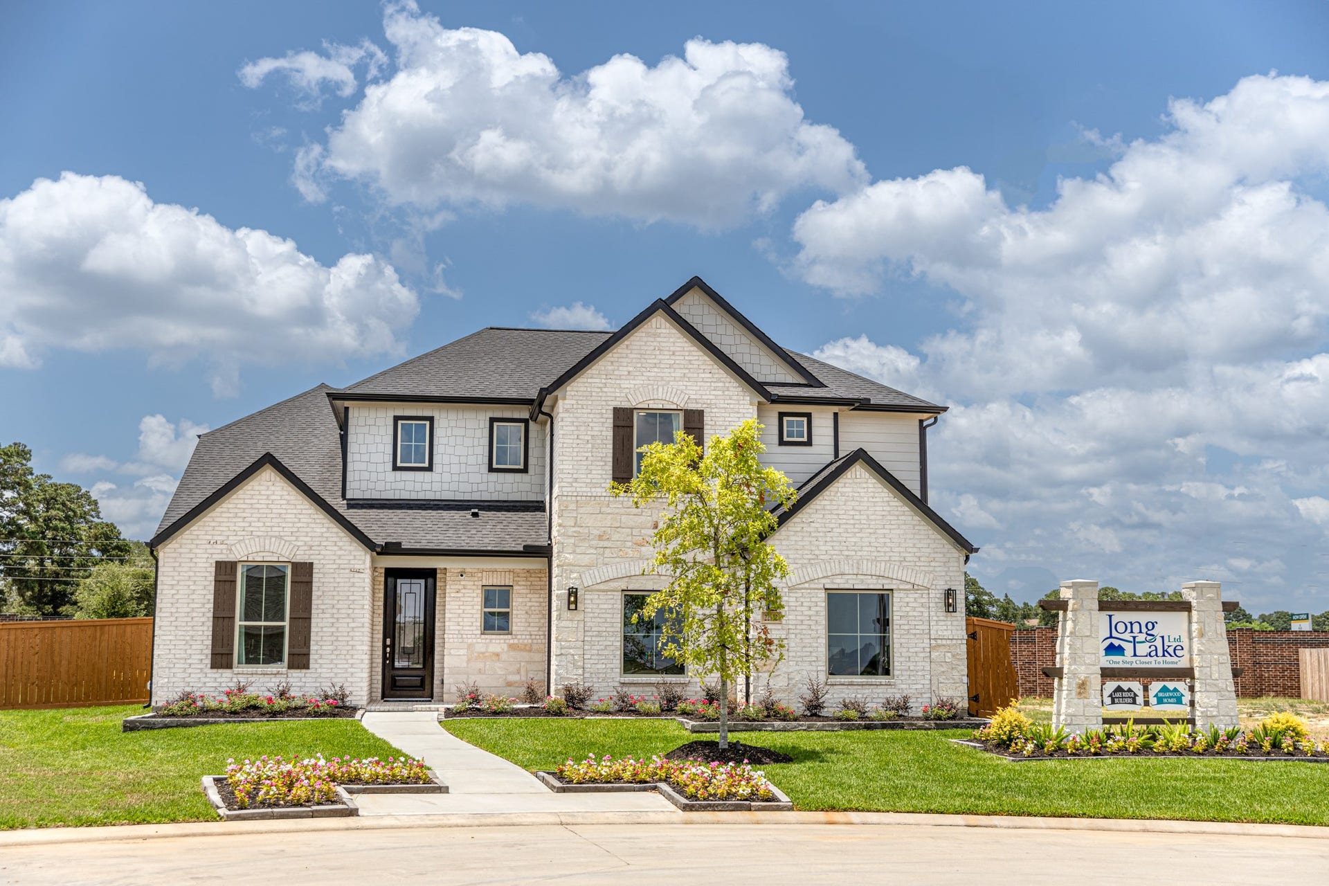 22122 Cortona Creek Lane, Hockley, TX 77447 This home boasts lush green grass and meticulous landscaping. Its premium elevation showcases an exquisite blend of brick and stone features, complemented by modern coach lighting