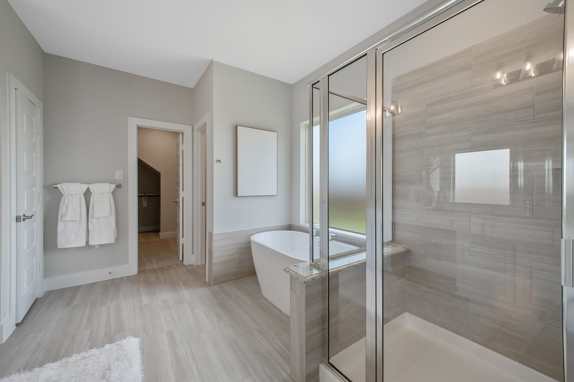 22122 Cortona Creek Lane, Hockley, TX 77447 Escape to a spa-like oasis in this primary bathroom. Enjoy a walk-in shower with tile surround, a separate garden tub with custom detailing, and an elegant vanity featuring light countertops, modern hardware, and beautiful vanity lights. Experience luxury and relaxation in every detail.