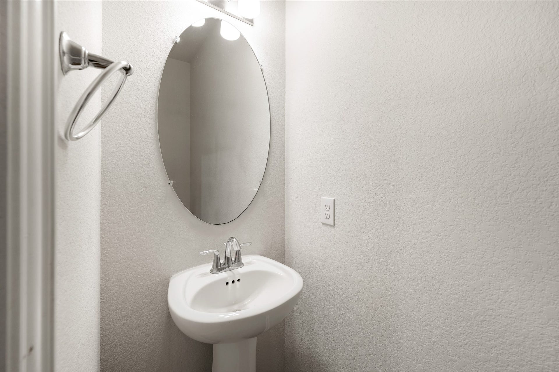 2418 Green Kale Drive, Richmond, TX 77406 Conveniently located for guests, the powder room features a pedestal sink, an elegant oval mirror, and a stylish vanity light, a clean and welcoming space!