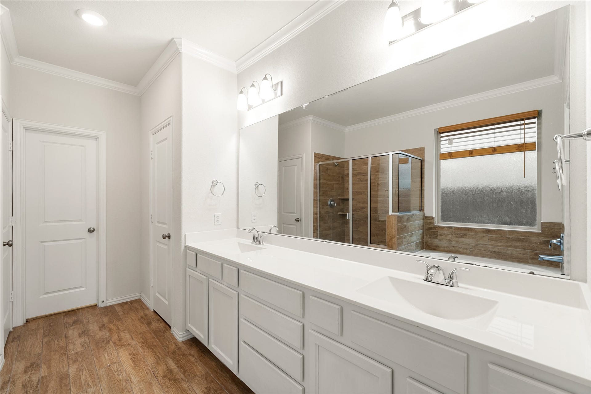 2418 Green Kale Drive, Richmond, TX 77406 The spa-like primary bath impresses with a dual-sink vanity, plenty of storage, a large mirror, crown molding, a separate glass-enclosed shower, and a relaxing garden tub!