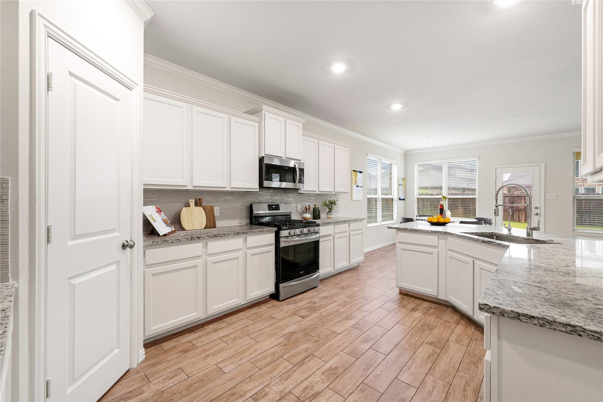 2418 Green Kale Drive, Richmond, TX 77406 This spacious kitchen boasts abundant white cabinetry and counter space, granite countertops, a tile backsplash, stainless steel appliances, and a center island with a deep sink. A large walk-in pantry and plenty of natural light complete the space! *Virtually Staged