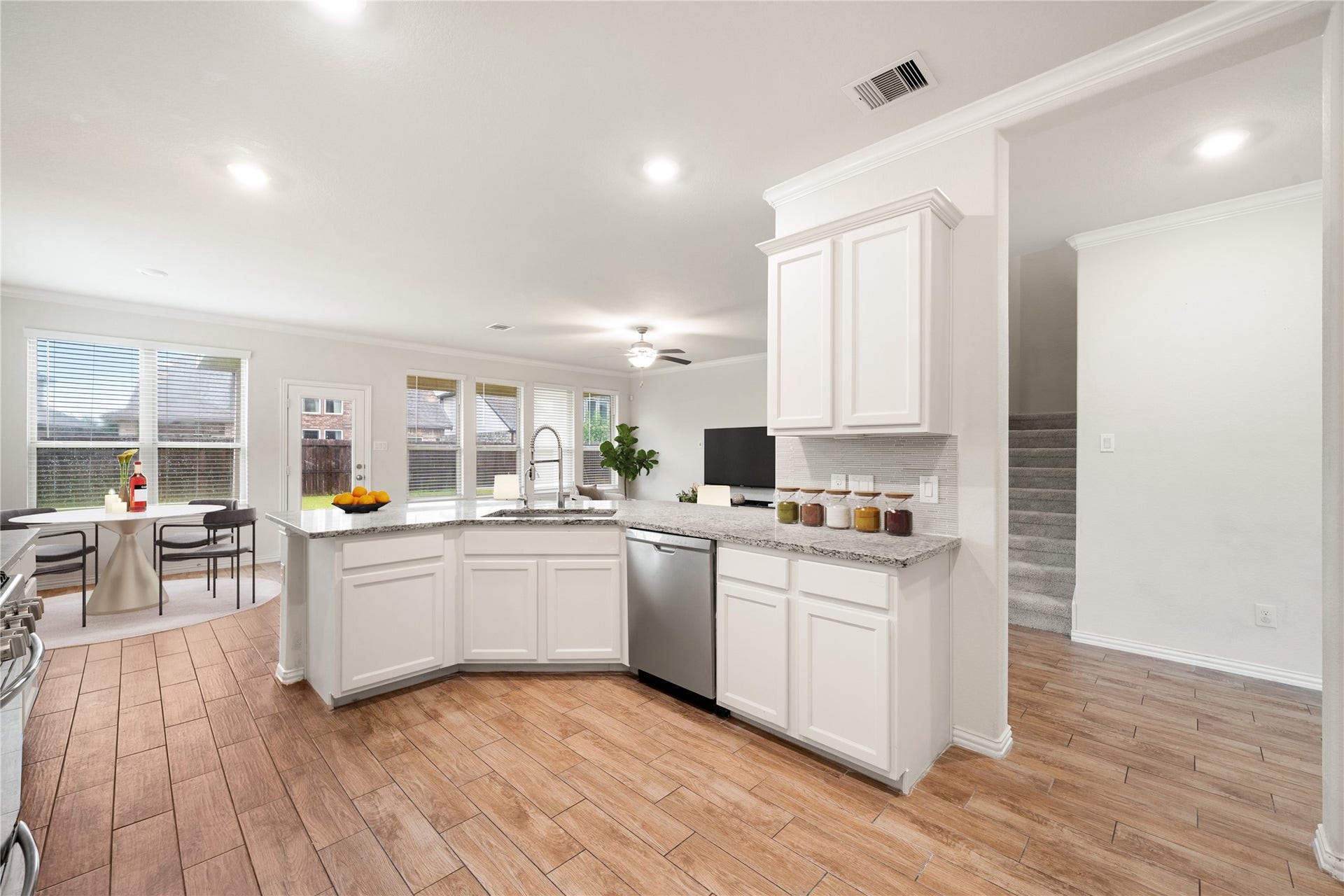 2418 Green Kale Drive, Richmond, TX 77406 Open and bright, the kitchen flows effortlessly into the breakfast nook and living area, ideal for everyday living! Featuring white cabinetry, granite countertops, stainless steel appliances, and a peninsula with bar seating, with the staircase just off to the side. *Virtually Staged