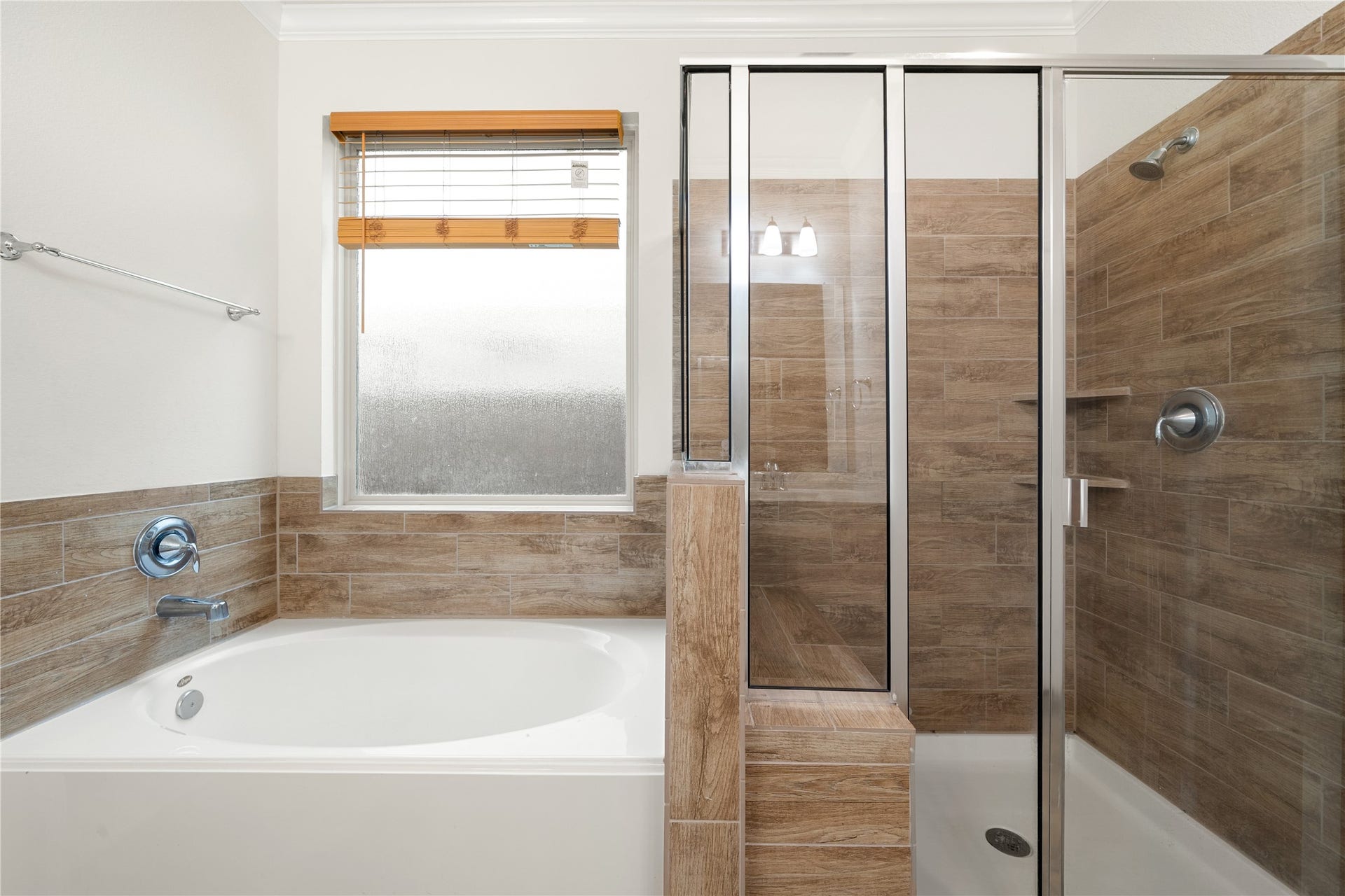 2418 Green Kale Drive, Richmond, TX 77406 Unwind in the luxurious primary bath, featuring a soaking garden tub, a separate walk-in shower with beautiful wood-look tile surround, and a frosted window for added privacy and natural light!