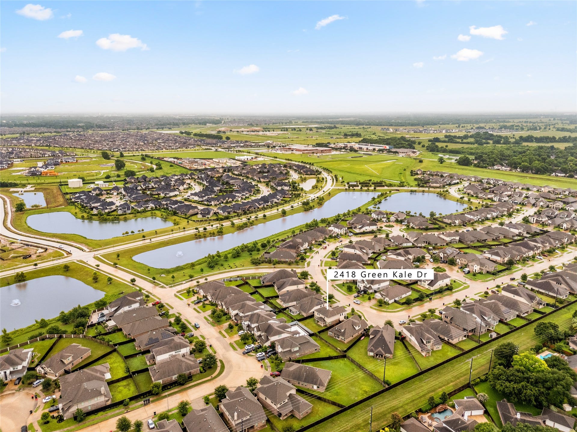 2418 Green Kale Drive, Richmond, TX 77406 Welcome to Harvest Green, a beautiful master-planned community in Richmond featuring scenic lakes, walking trails, and resort-style amenities. This aerial view showcases 2418 Green Kale Drive's prime location just steps from the water and surrounded by greenspace!