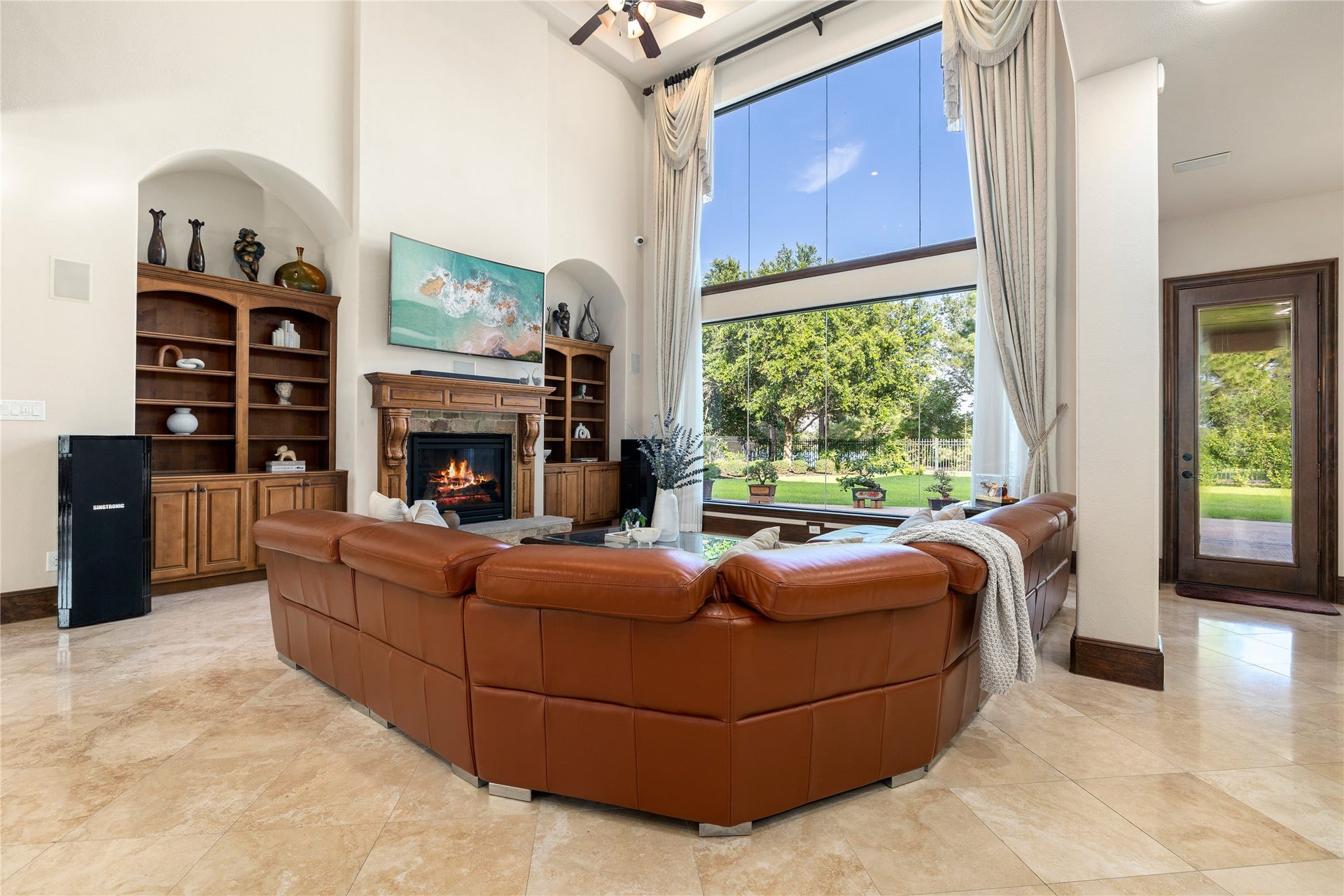 27711 Charter Lake Lane, Katy, TX 77494 Spacious family room with custom built-ins, statement fireplace, soaring ceilings, and breathtaking waterfront views.