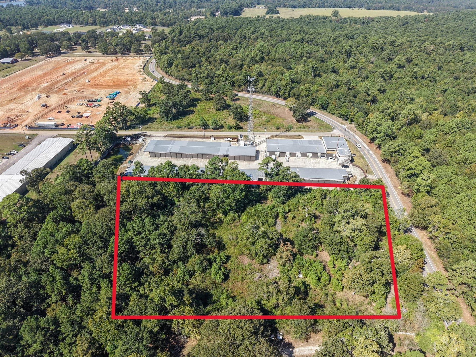 18841 W Fm 1097 Road, Montgomery, TX 77356 Elevated aerial perspective showcasing the property's layout, mature trees, and proximity to neighboring commercial facilities. Nearby development activity highlights the area's evolving landscape.