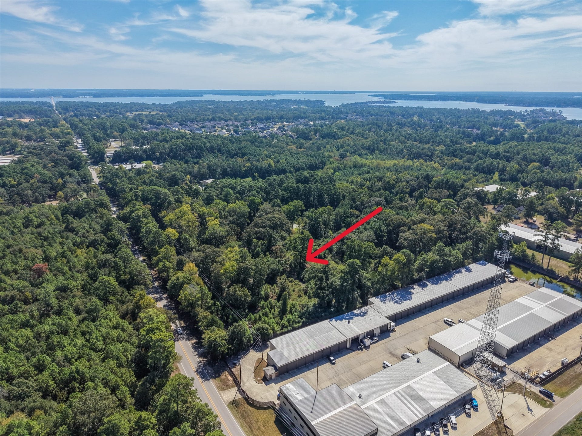 18841 W Fm 1097 Road, Montgomery, TX 77356 Scenic aerial view highlighting the property's location among mature trees, established commercial facilities, and nearby Lake Conroe. The surrounding area offers a blend of natural beauty and accessibility.