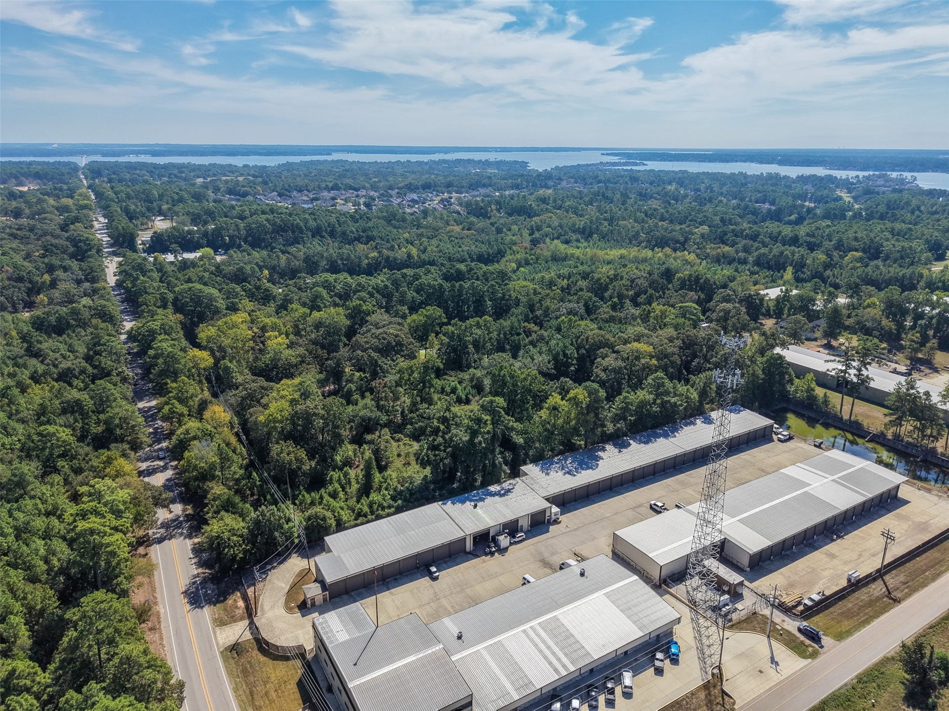18841 W Fm 1097 Road, Montgomery, TX 77356 Wide-angle aerial showcasing the heavily wooded surroundings, nearby roadway, and expansive views toward Lake Conroe. An excellent perspective of the property's location within the growing Lake Conroe area.
