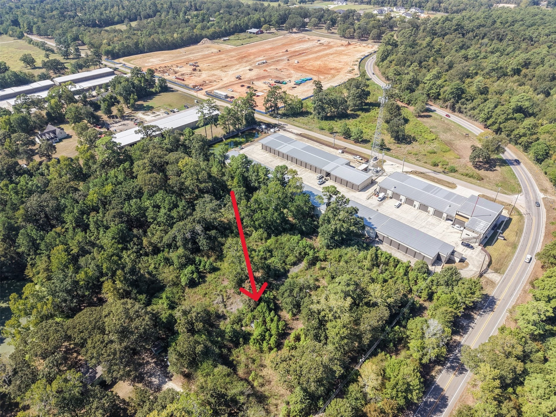 18841 W Fm 1097 Road, Montgomery, TX 77356 Expansive aerial view capturing the property's wooded terrain, surrounding roadways, and nearby commercial development. A desirable location offering potential for a variety of future uses.