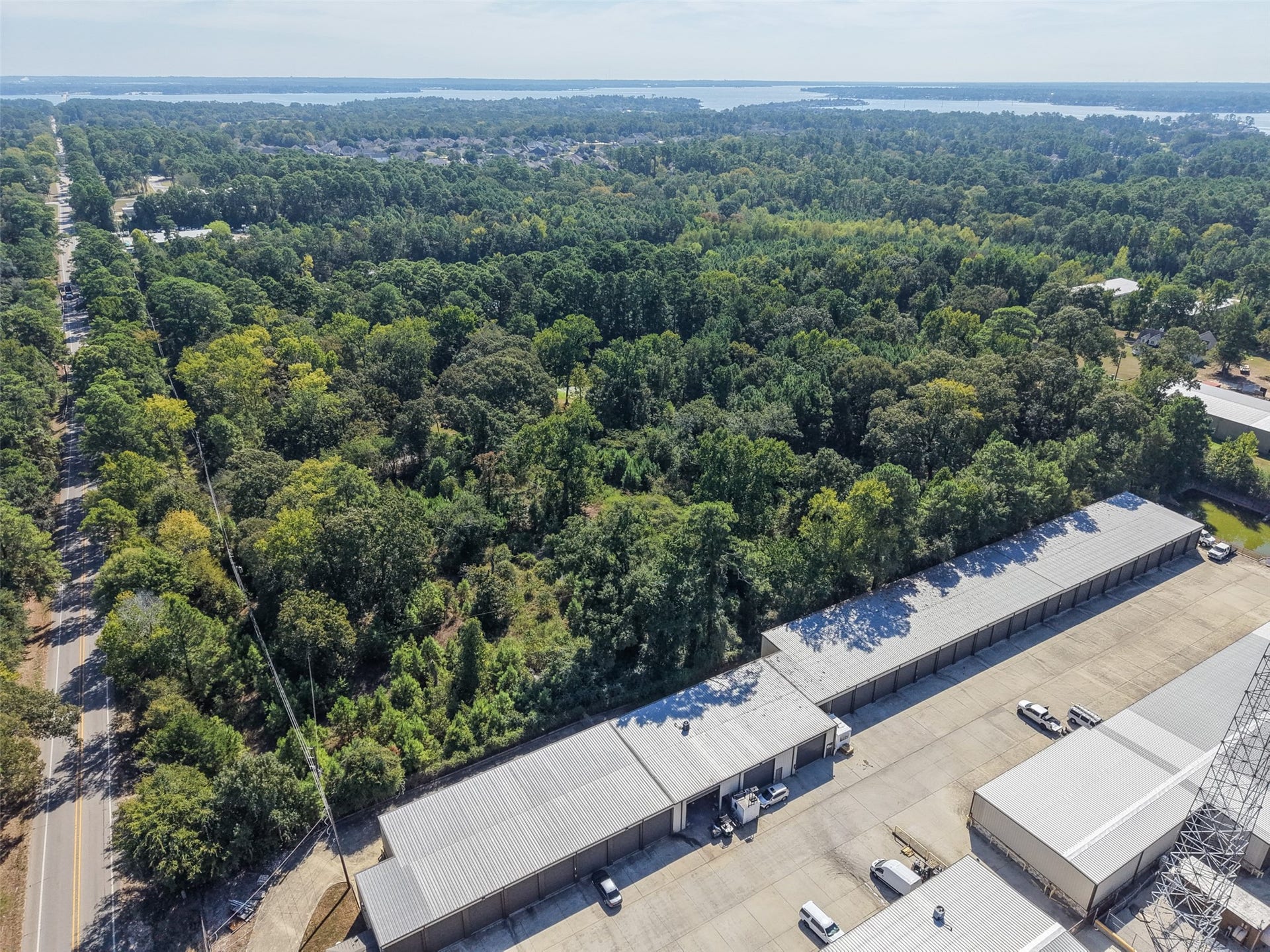 18841 W Fm 1097 Road, Montgomery, TX 77356 Wide-angle aerial showcasing the heavily wooded surroundings, nearby roadway, and expansive views toward Lake Conroe. An excellent perspective of the property's location within the growing Lake Conroe area.