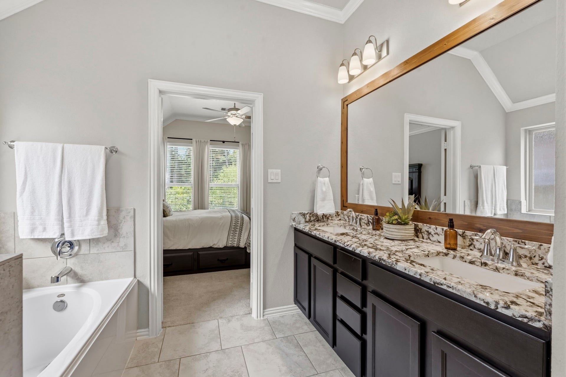 2143 Moss Creek Lane, Conroe, TX 77304 The beautifully finished primary bath features upgraded granite countertops, dual vanities, a custom framed mirror, a soaking tub, separate glass-enclosed shower, a private water closet, and a spacious walk-in closet.