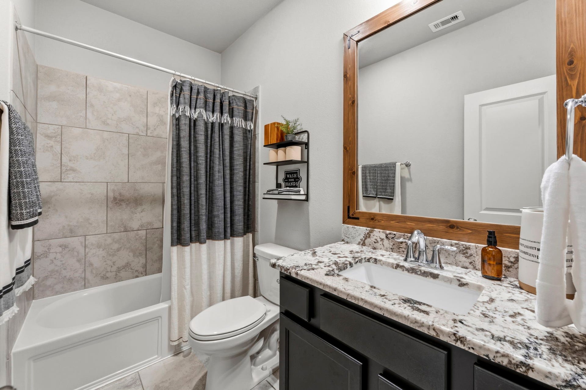 2143 Moss Creek Lane, Conroe, TX 77304 The second full hall bathroom showcases an upgraded granite countertop and custom framed mirror.