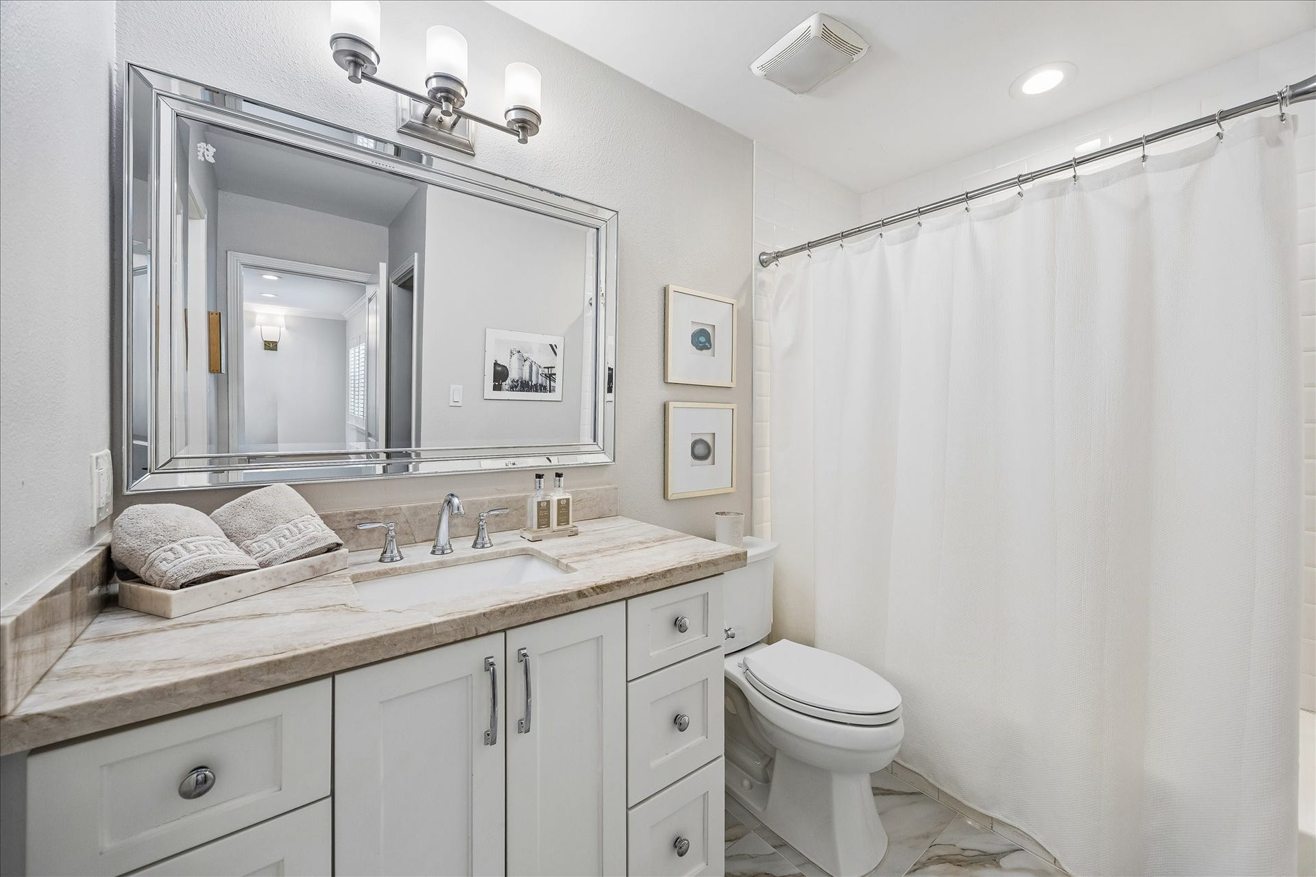 2555 Bering Drive, #11, Houston, TX 77057 This secondary bathroom has been fully remodeled, featuring natural quartzite countertops, premium porcelain tile, and an upgraded decorative light fixture and mirror.