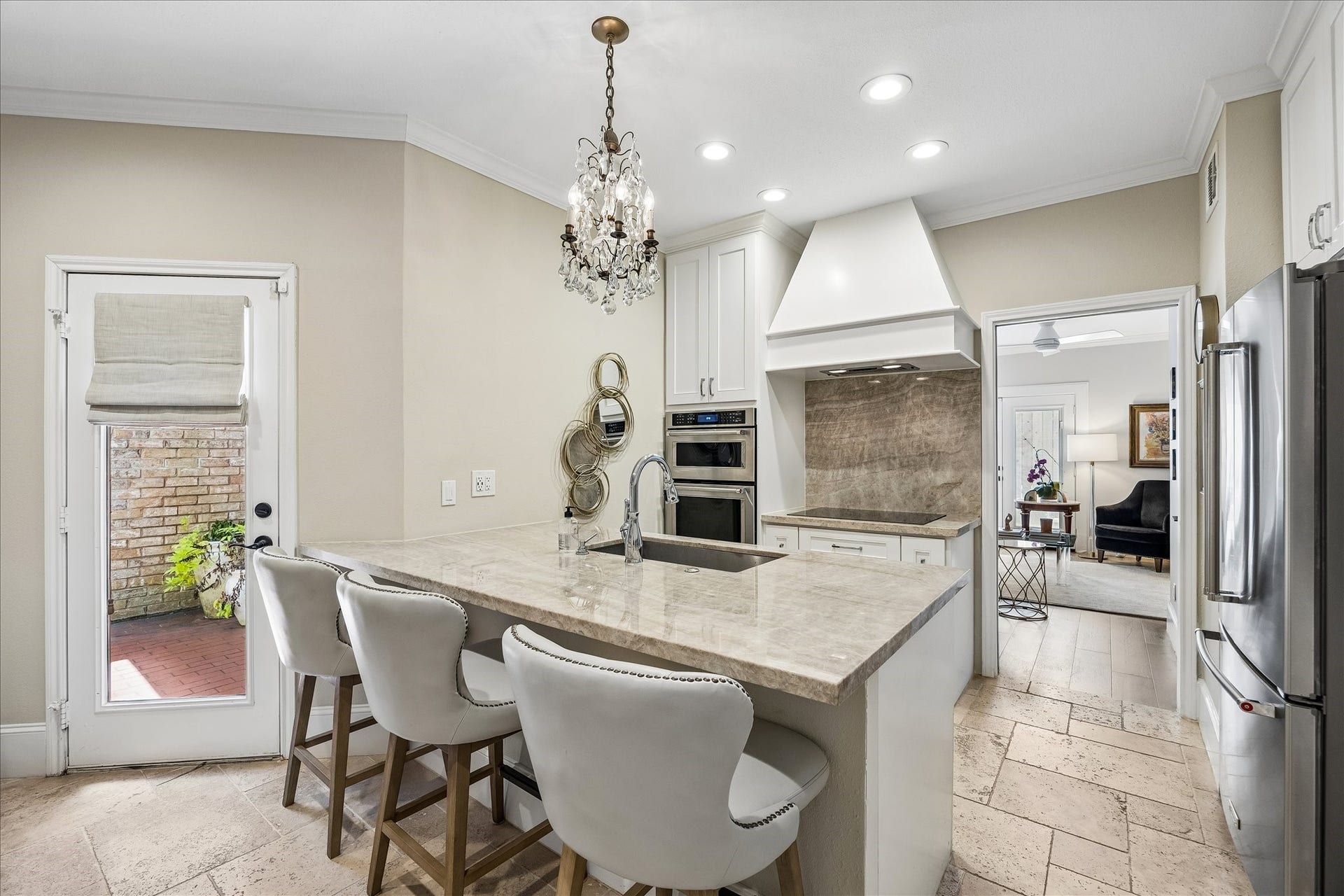 2555 Bering Drive, #11, Houston, TX 77057 This exceptional custom kitchen is appointed with Travertine flooring, quartzite natural stone countertops and backsplashes, premium double ovens, and a high CMU vent hood, offering a premier culinary environment.
