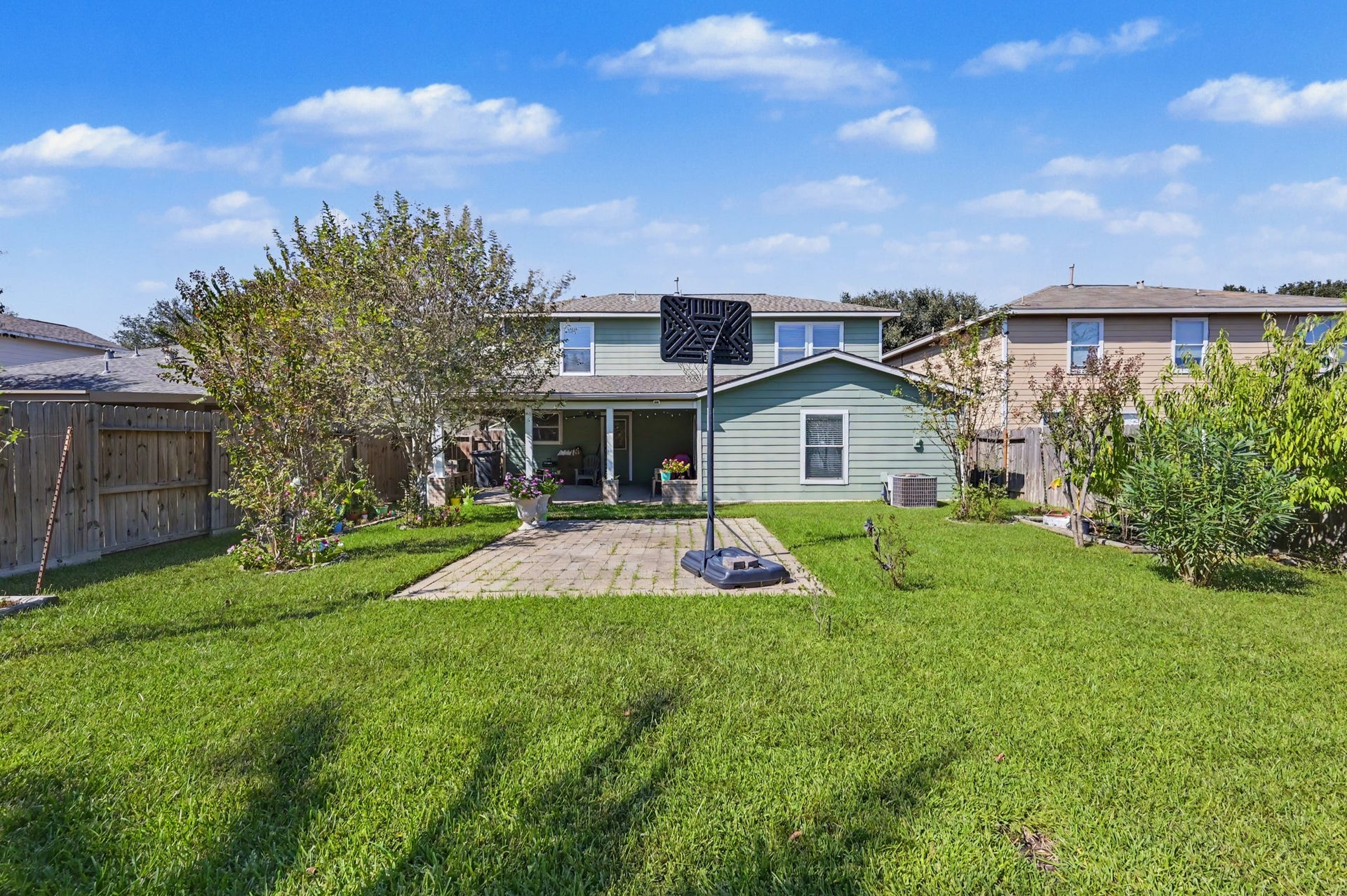 1819 Emerald Pathway Drive, Spring, TX 77388 Spacious backyard featuring lush green lawn, mature trees, and a paved patio area perfect for outdoor activities and relaxation.
