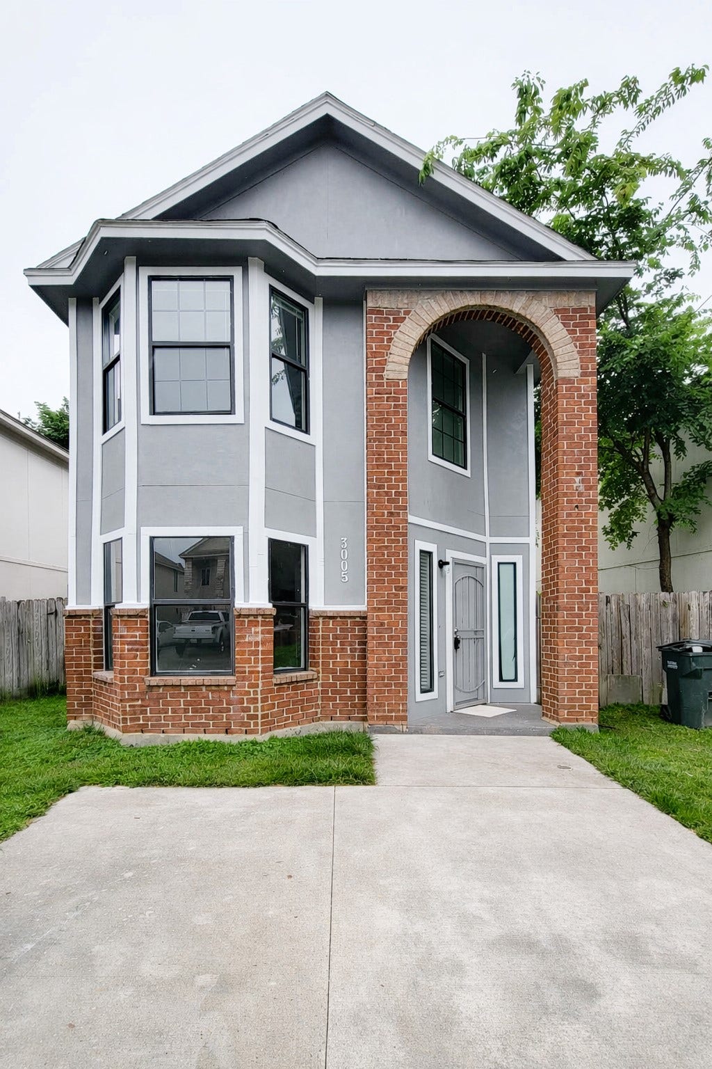 3005 La Estancia Lane, Houston, TX 77093 Charming two-story home featuring a striking combination of gray siding and brick accents, with a welcoming arched entry and large bay windows.