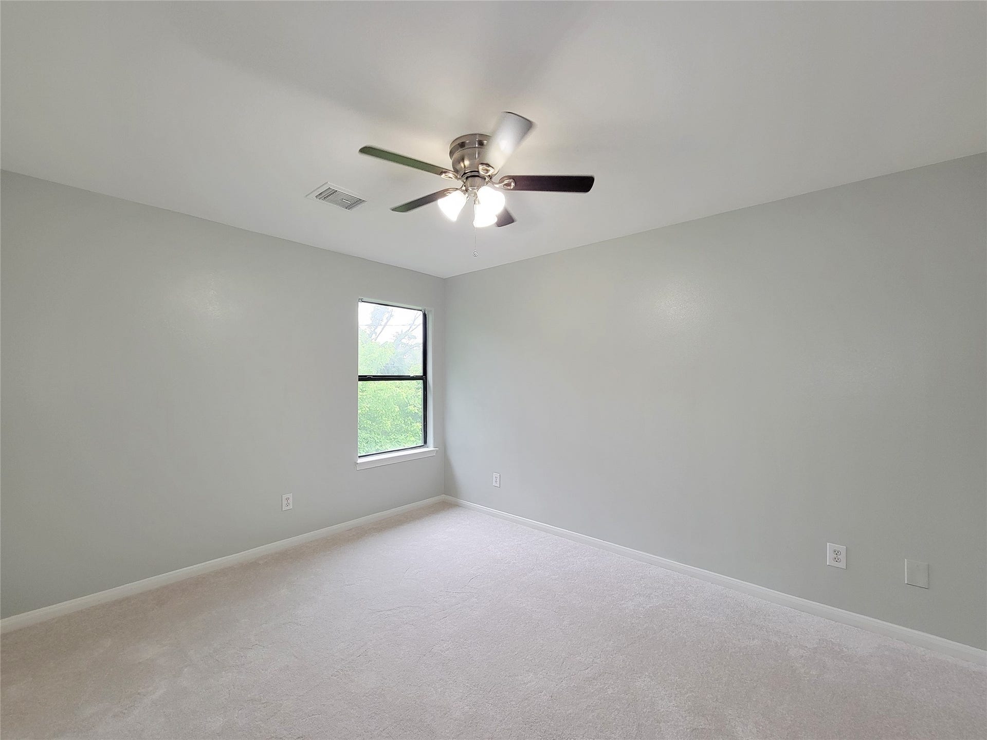3005 La Estancia Lane, Houston, TX 77093 Bright and spacious bedroom featuring soft gray walls, plush carpeting, a large window for natural light, and a modern ceiling fan for comfort.