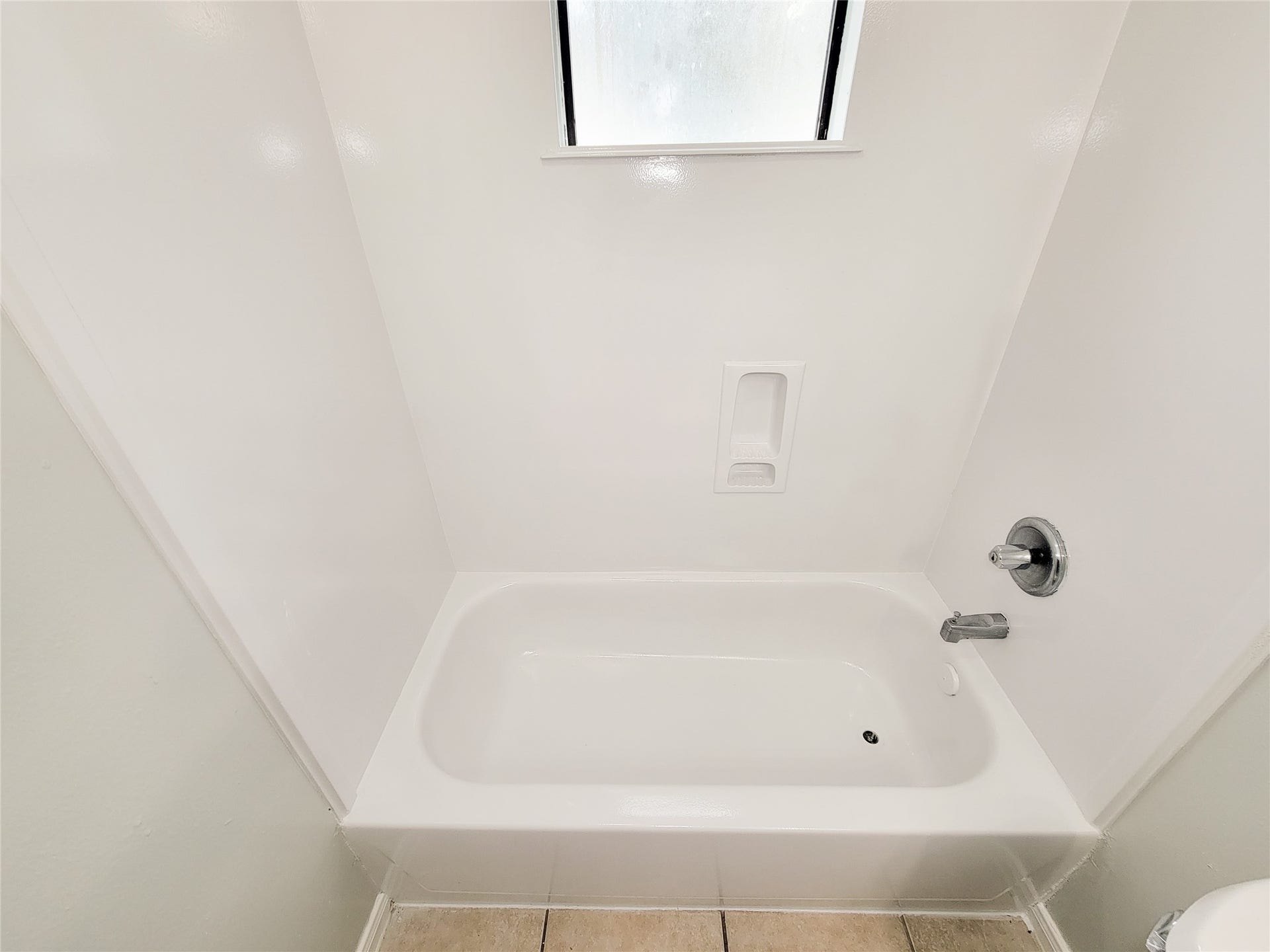 3005 La Estancia Lane, Houston, TX 77093 A pristine, white bathtub with modern fixtures, accompanied by a frosted window for natural light and privacy.