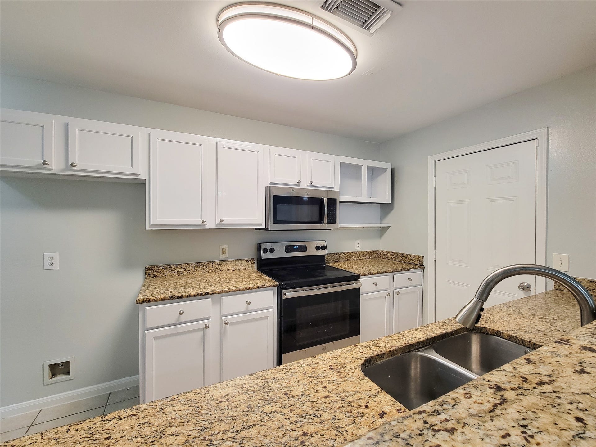 3005 La Estancia Lane, Houston, TX 77093 Modern kitchen with sleek granite countertops, stainless steel appliances, and ample white cabinetry for storage.