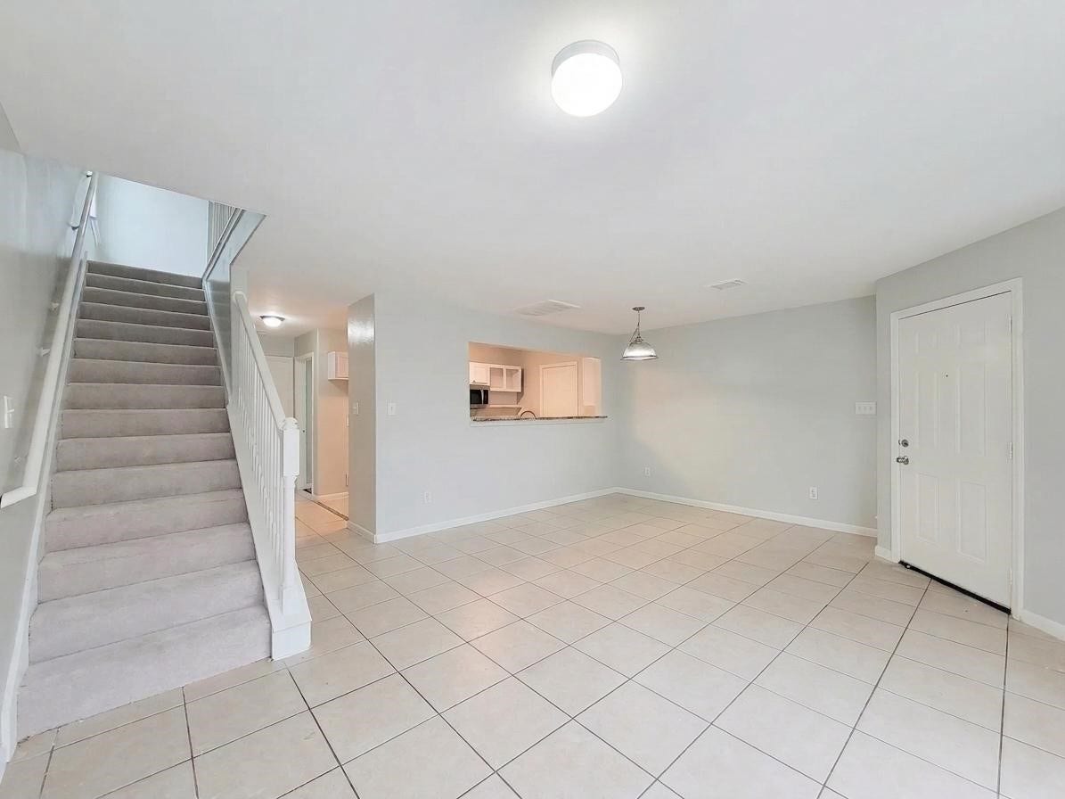 3005 La Estancia Lane, Houston, TX 77093 Bright and spacious living area with tiled flooring, a cozy dining nook, and easy access to the kitchen. A carpeted staircase leads to the upper level, creating a welcoming atmosphere.