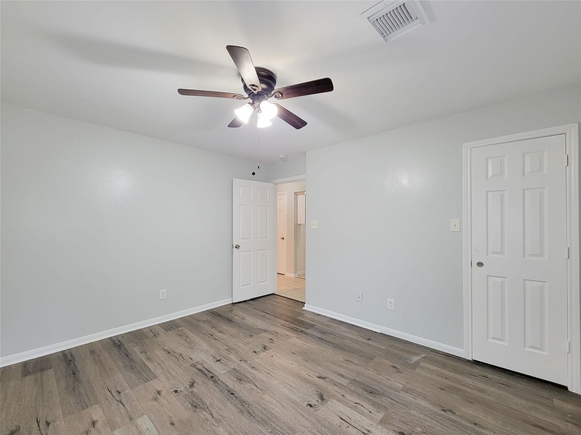 3005 La Estancia Lane, Houston, TX 77093 Bright and airy room featuring sleek wood flooring, neutral walls, and a modern ceiling fan, ideal for a cozy living space.