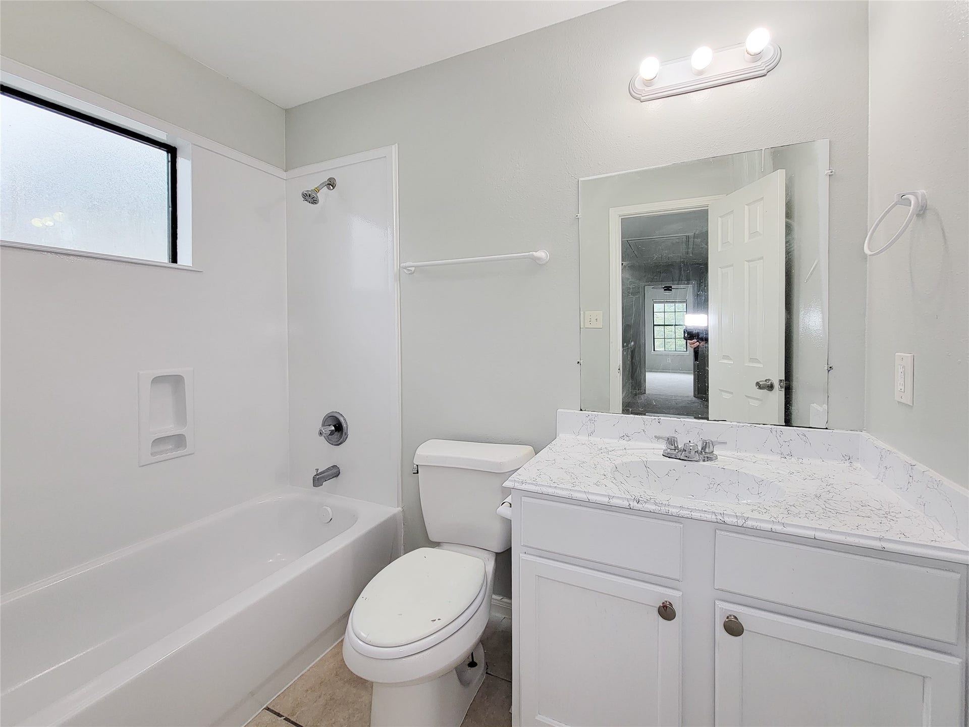 3005 La Estancia Lane, Houston, TX 77093 Bright and modern bathroom featuring a sleek vanity with a marble countertop, a full bathtub, and ample natural light from the frosted window.