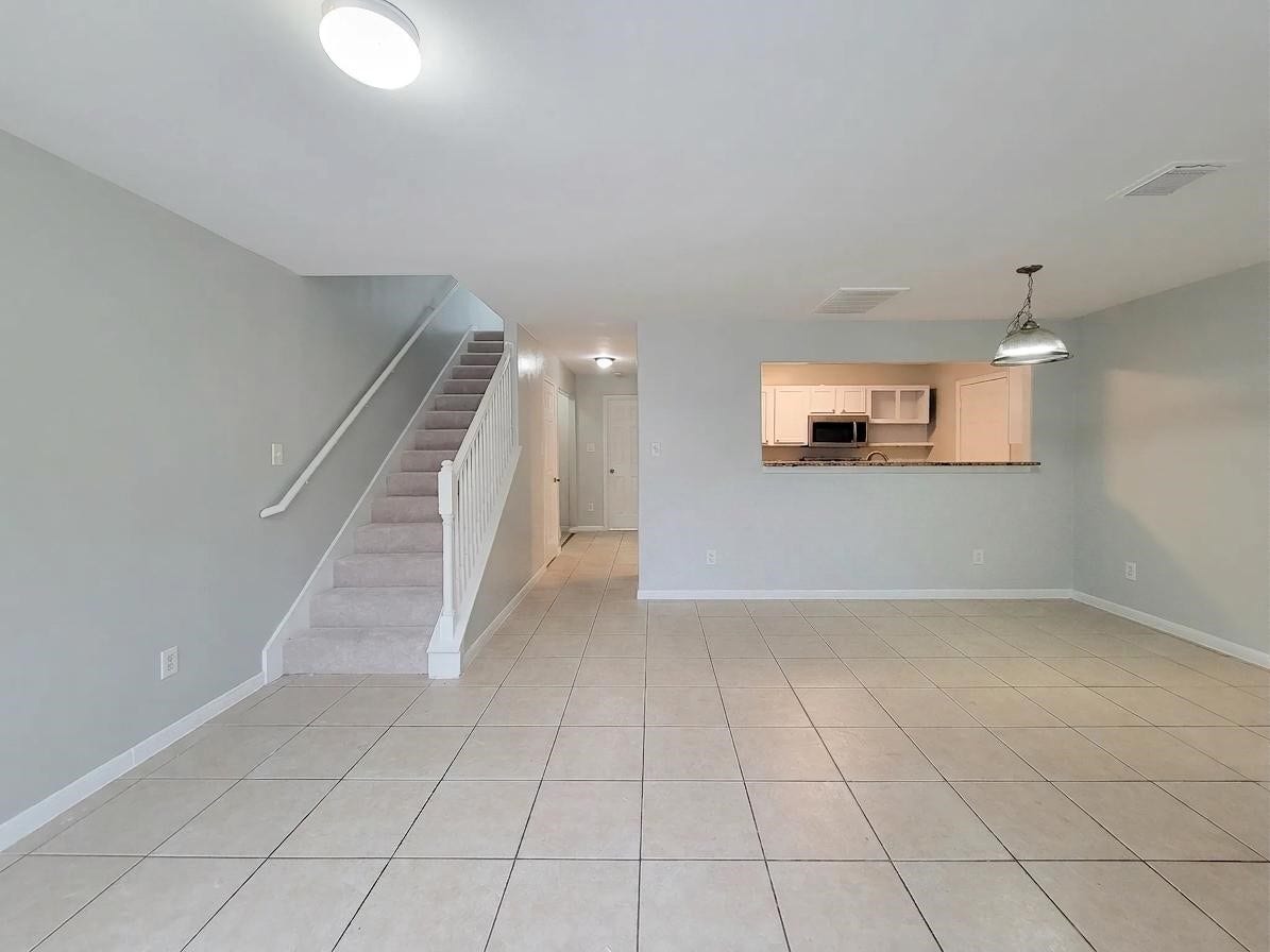 3005 La Estancia Lane, Houston, TX 77093 Spacious open-plan living area with tiled flooring, neutral walls, and a view into the modern kitchen. A staircase leads to the upper level, enhancing the home's layout.