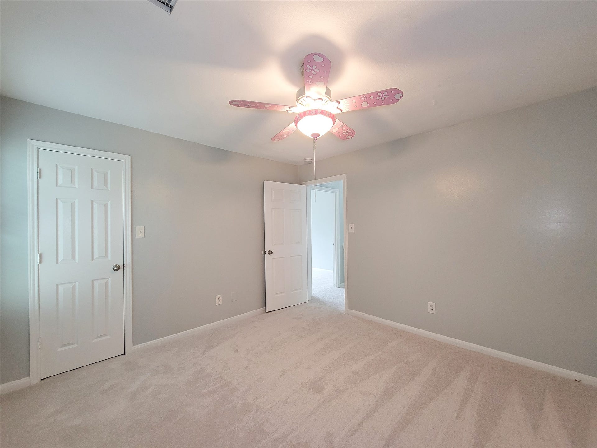 3005 La Estancia Lane, Houston, TX 77093 Bright and inviting bedroom featuring soft gray walls, plush carpet, and a playful pink ceiling fan, offering a cozy and cheerful ambiance.