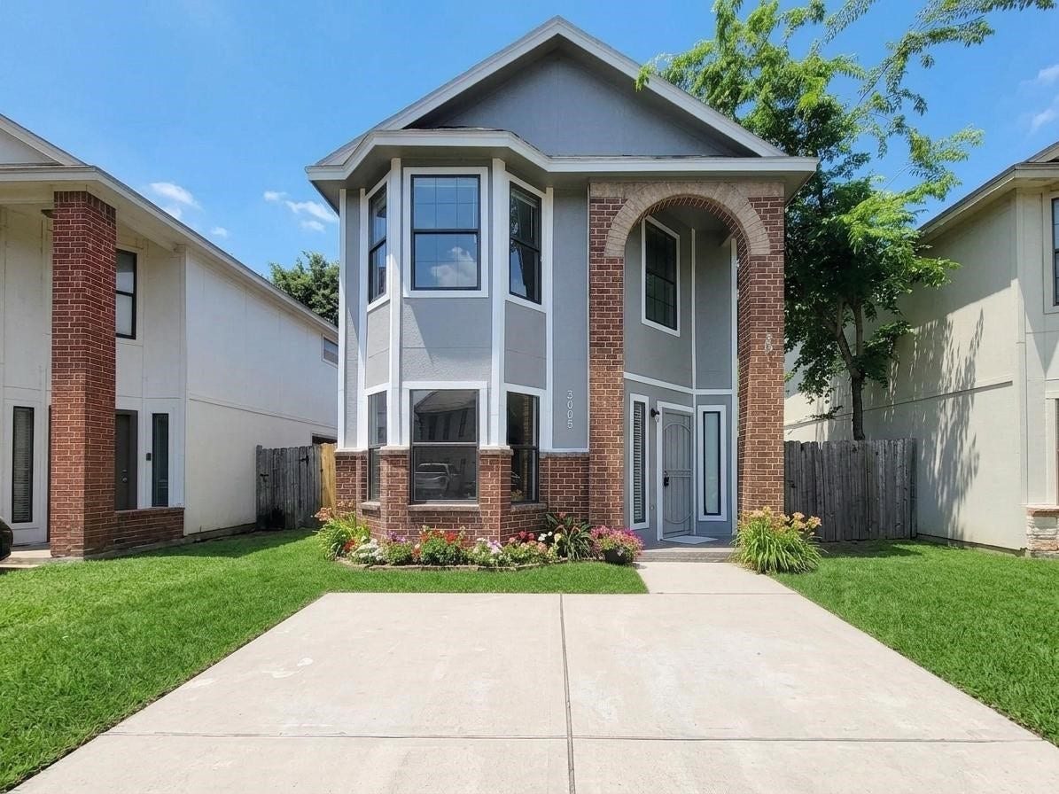 3005 La Estancia Lane, Houston, TX 77093 Charming two-story home with elegant brick accents, lush green lawn, and vibrant flowers framing the entrance for a welcoming curb appeal.