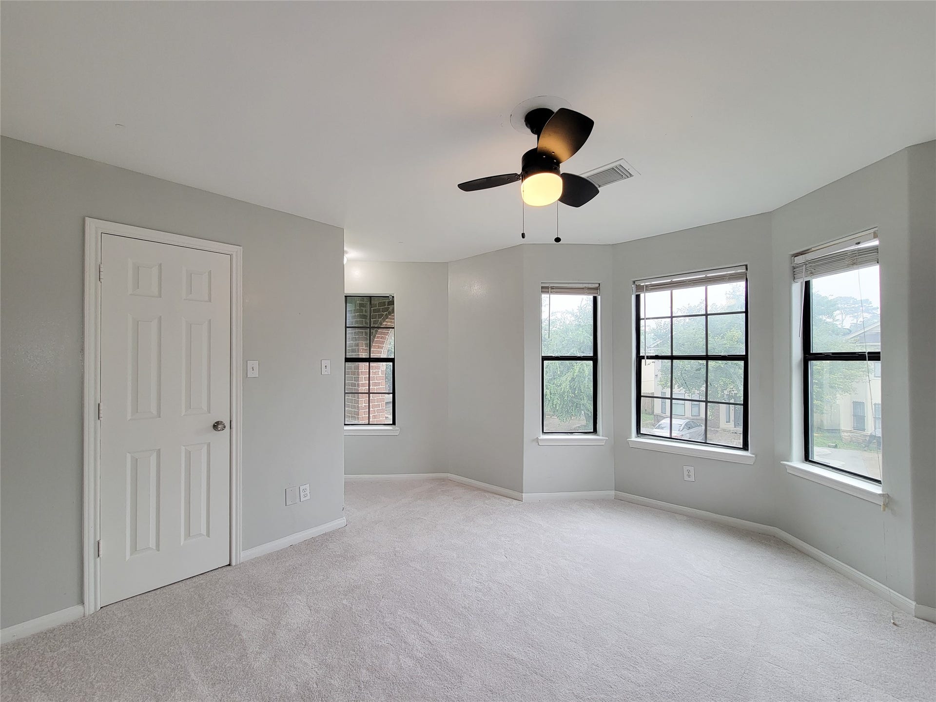 3005 La Estancia Lane, Houston, TX 77093 Bright and spacious bedroom featuring large windows, a modern ceiling fan, and soft carpeting, creating a comfortable and inviting atmosphere.