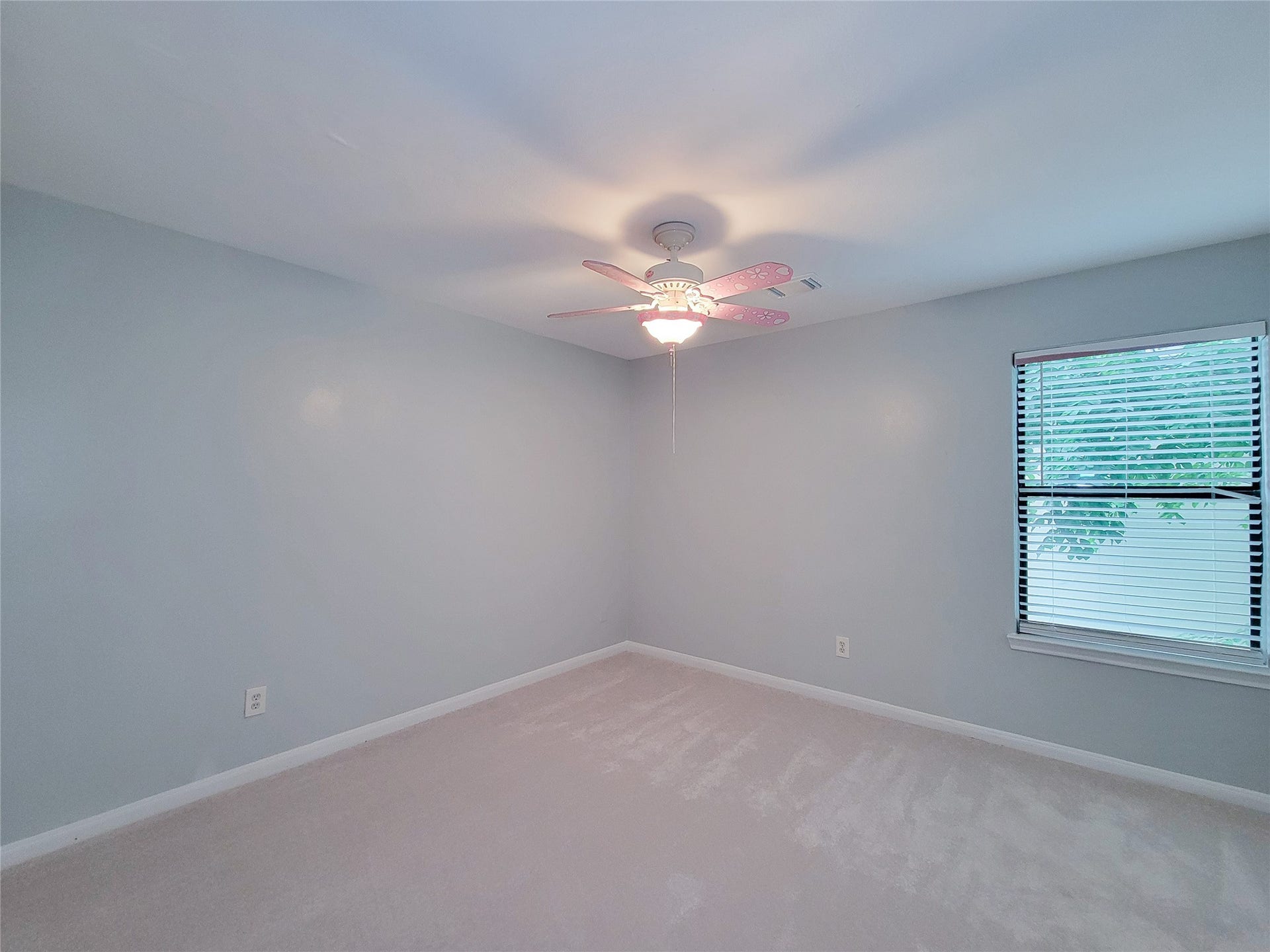 3005 La Estancia Lane, Houston, TX 77093 Bright and airy bedroom with soft gray walls, a whimsical ceiling fan, and a window that lets in plenty of natural light.